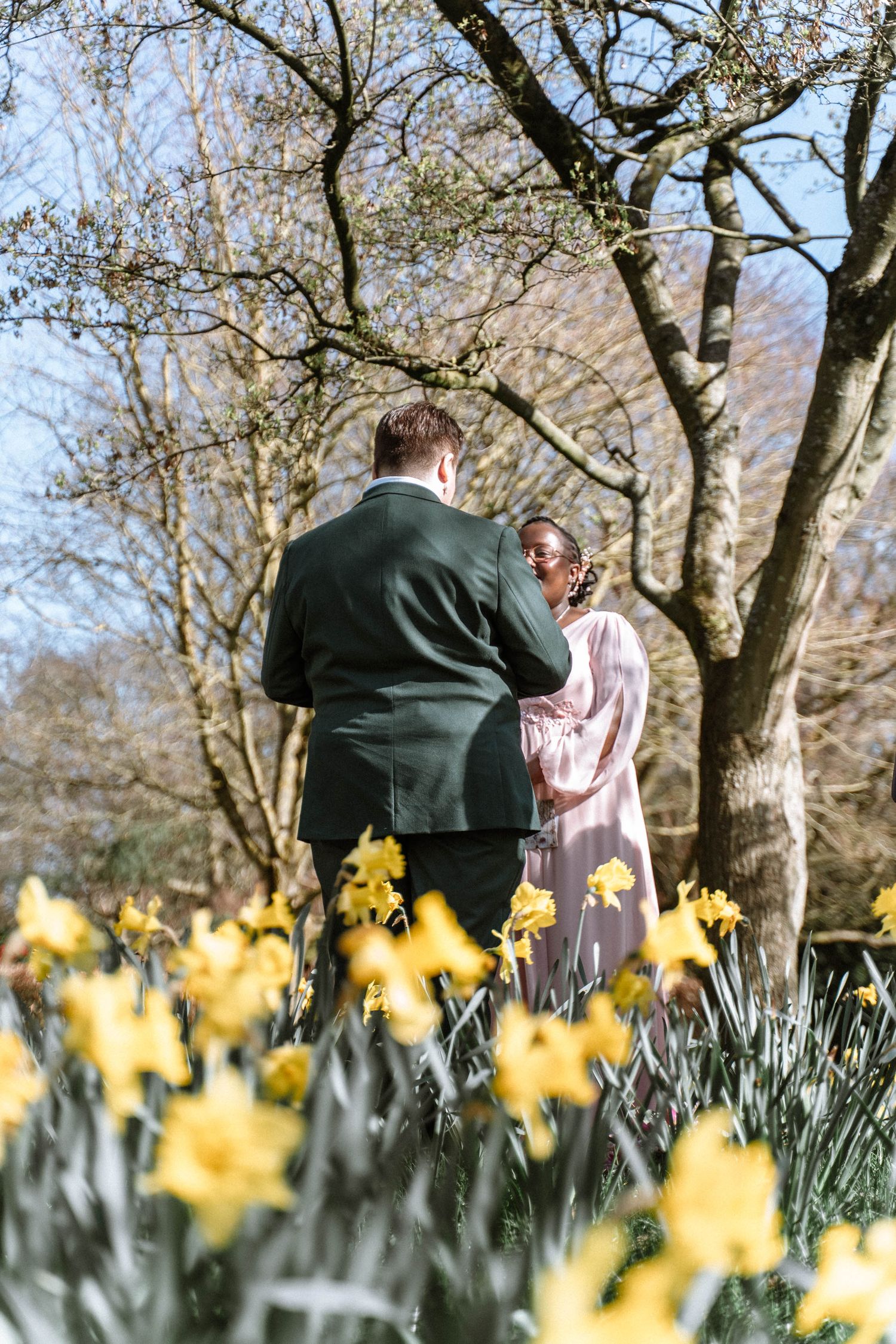 Couple standing together among flowers during Manchester LGBTQ wedding ceremony