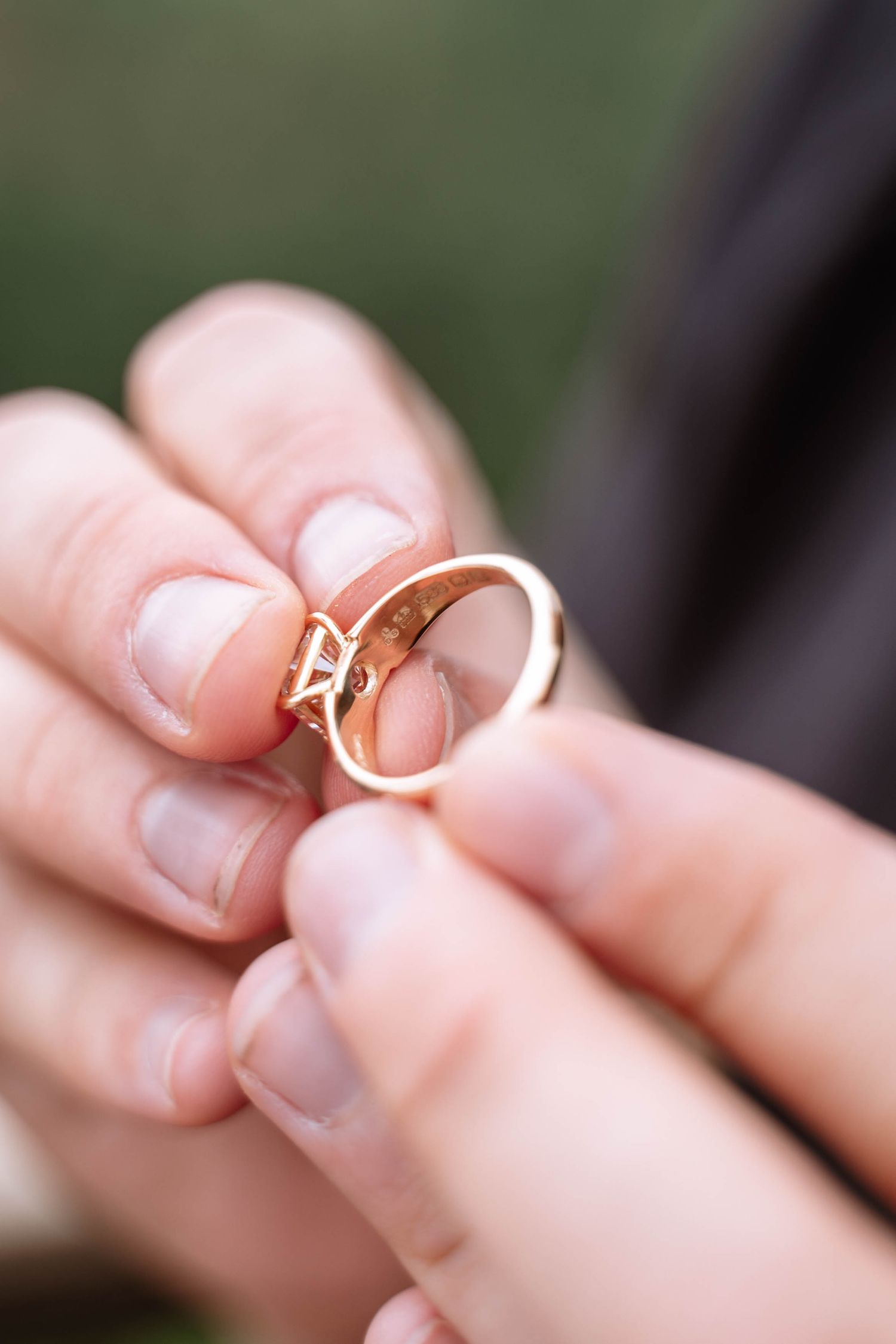 Close-up of one gold ring held between the couple’s fingers.