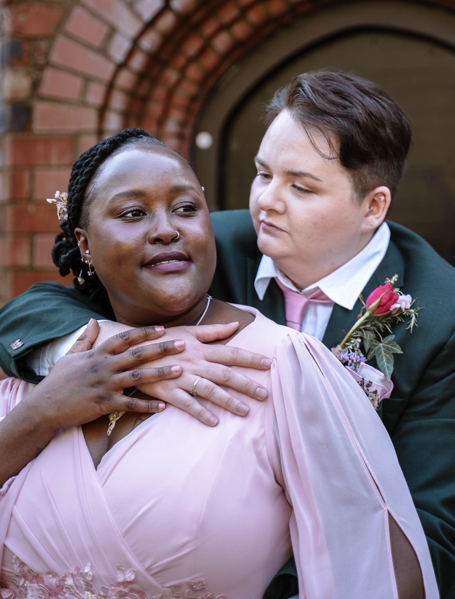 Couple embracing under brick arch during Manchester LGBTQ wedding