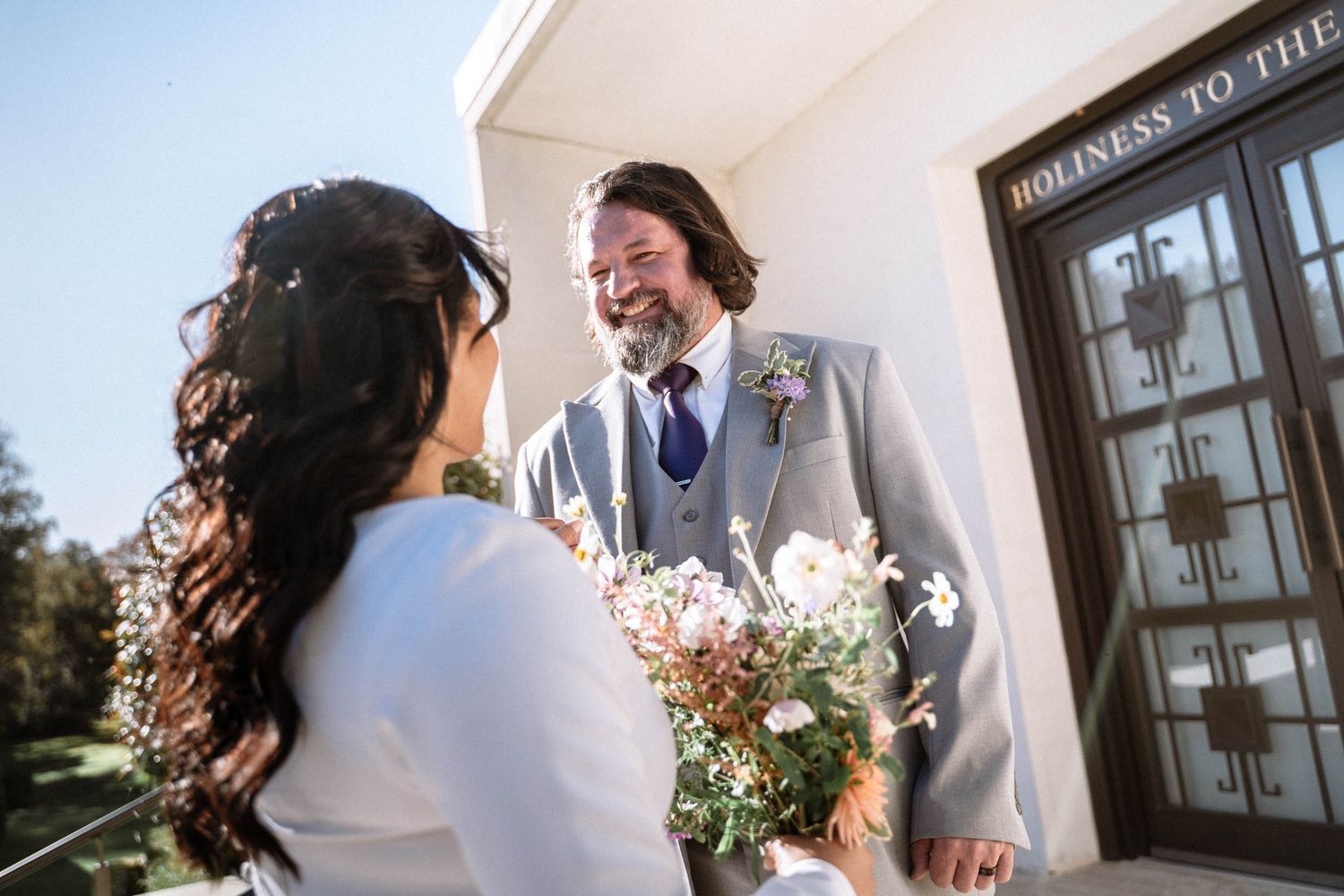 Couple smiling outside LDS temple during wedding portraits