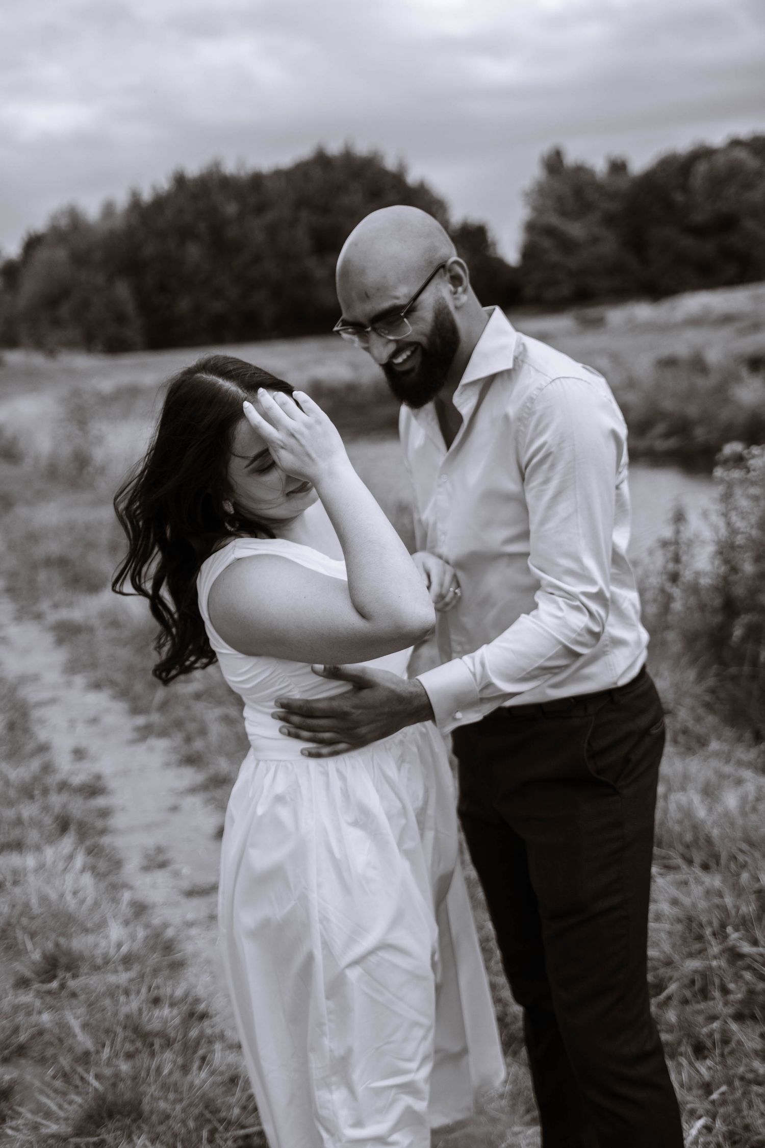 Couple embracing in an open meadow during their Fletcher Moss Park proposal in black and white