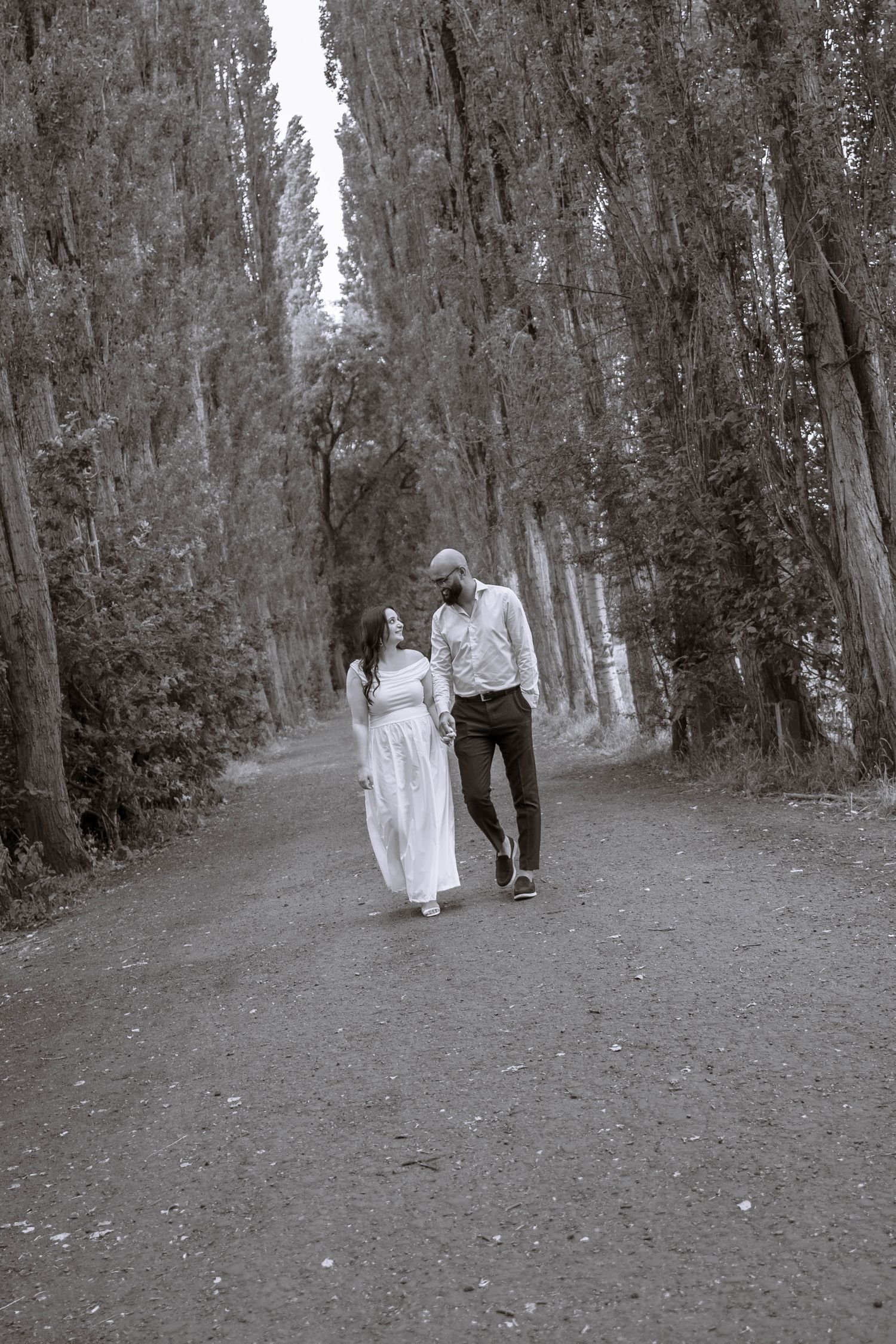 Couple walking together along a tree-lined avenue at Fletcher Moss Park, Manchester