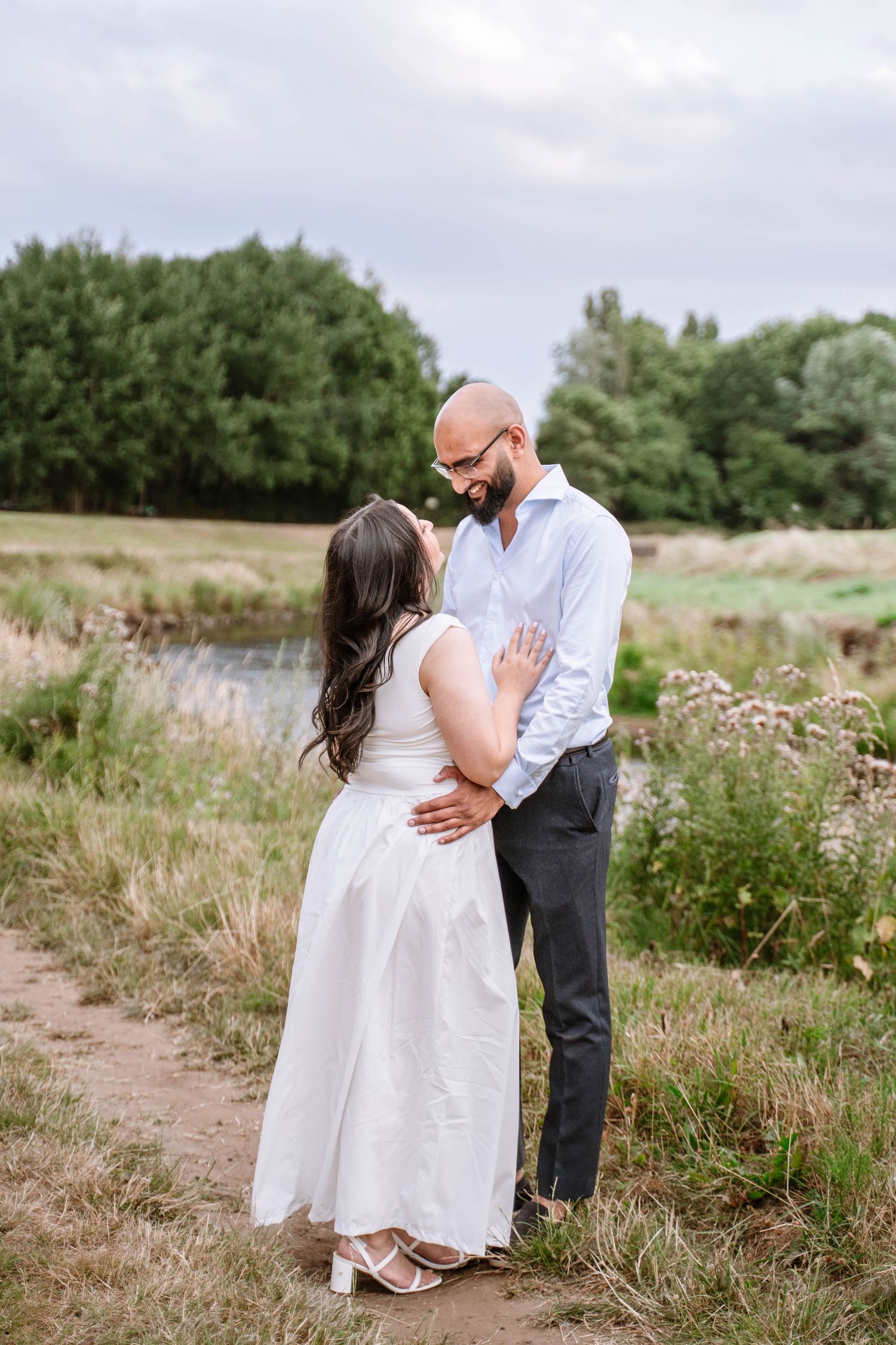 Couple hugging each other outdoors in a field during a Manchester proposal