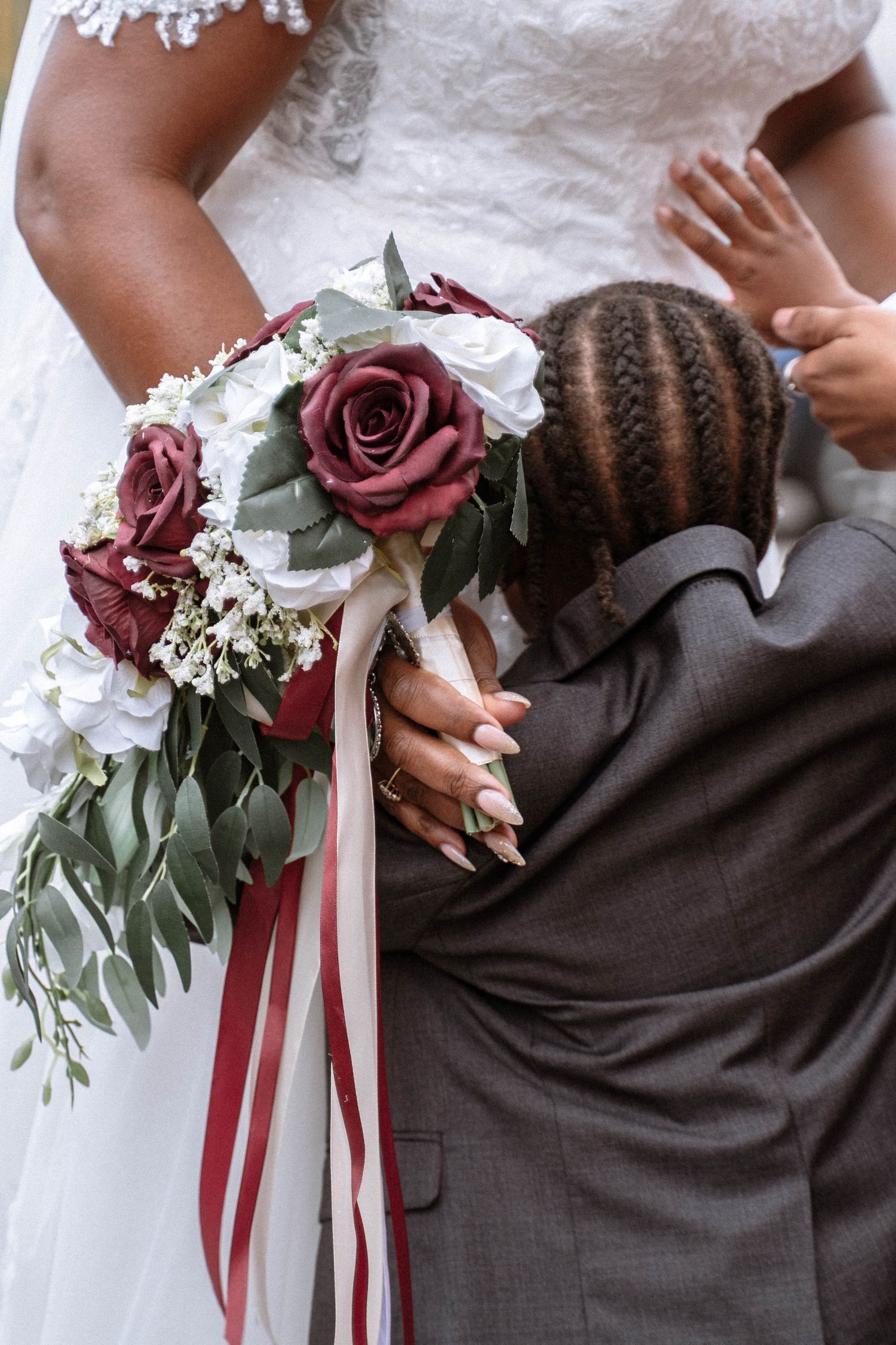 Bride holding bouquet while child hugs her during Jamaican church wedding in Birmingham