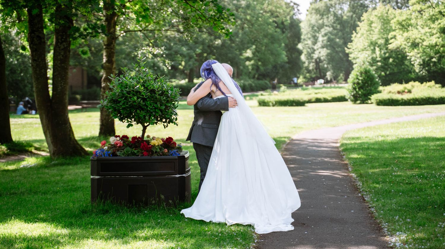 Bride and Dad hugging each other outside The Lodge, Mesnes Park in Wigan