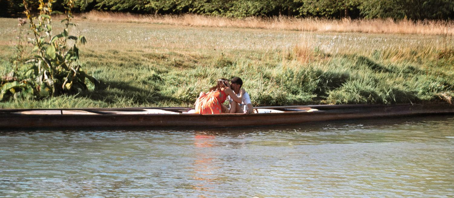 Couple embracing in a punt on the River Cam during their Cambridge punt proposal