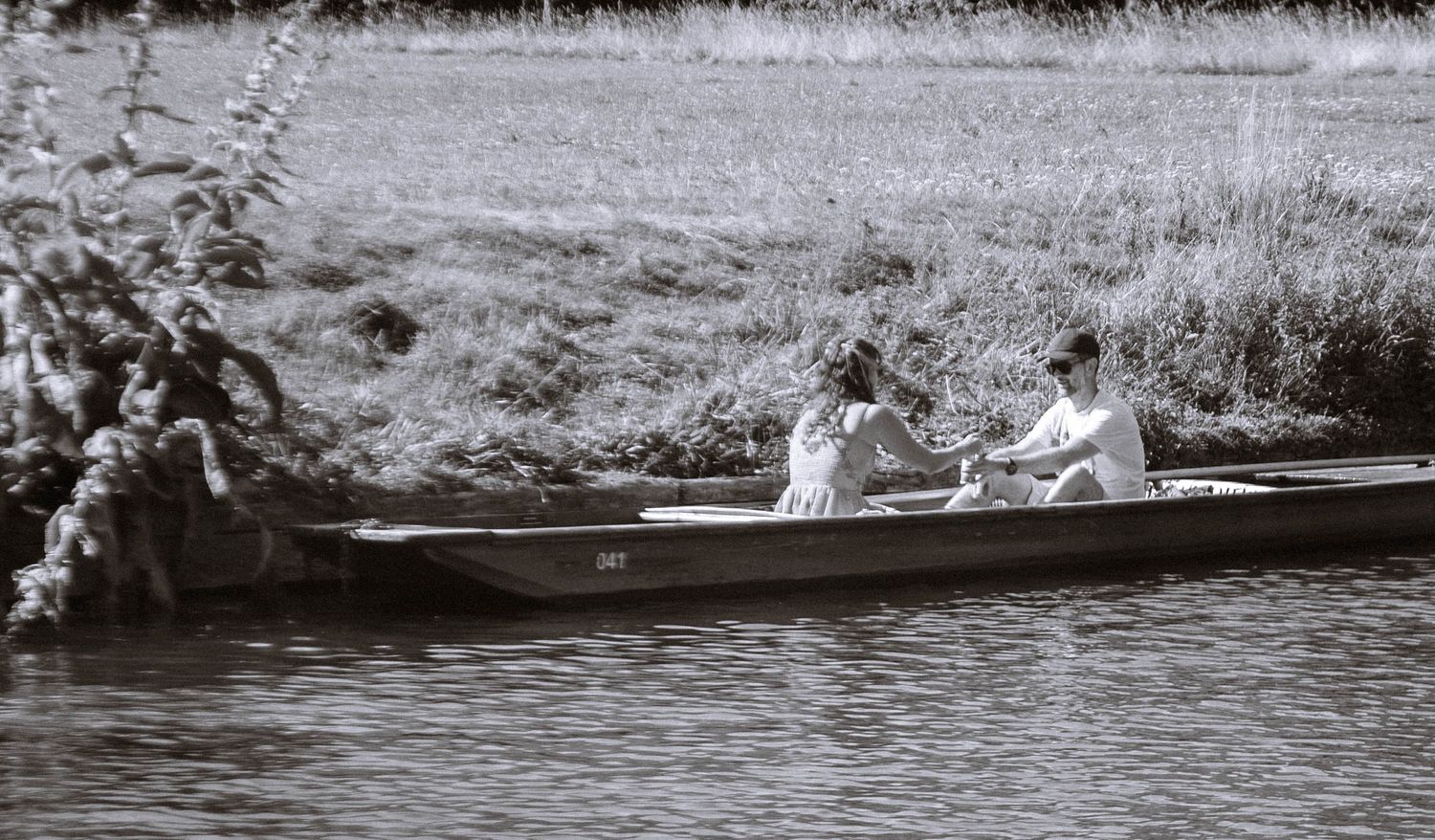 Couple sitting together in a punt on the River Cam, photographed in black and white