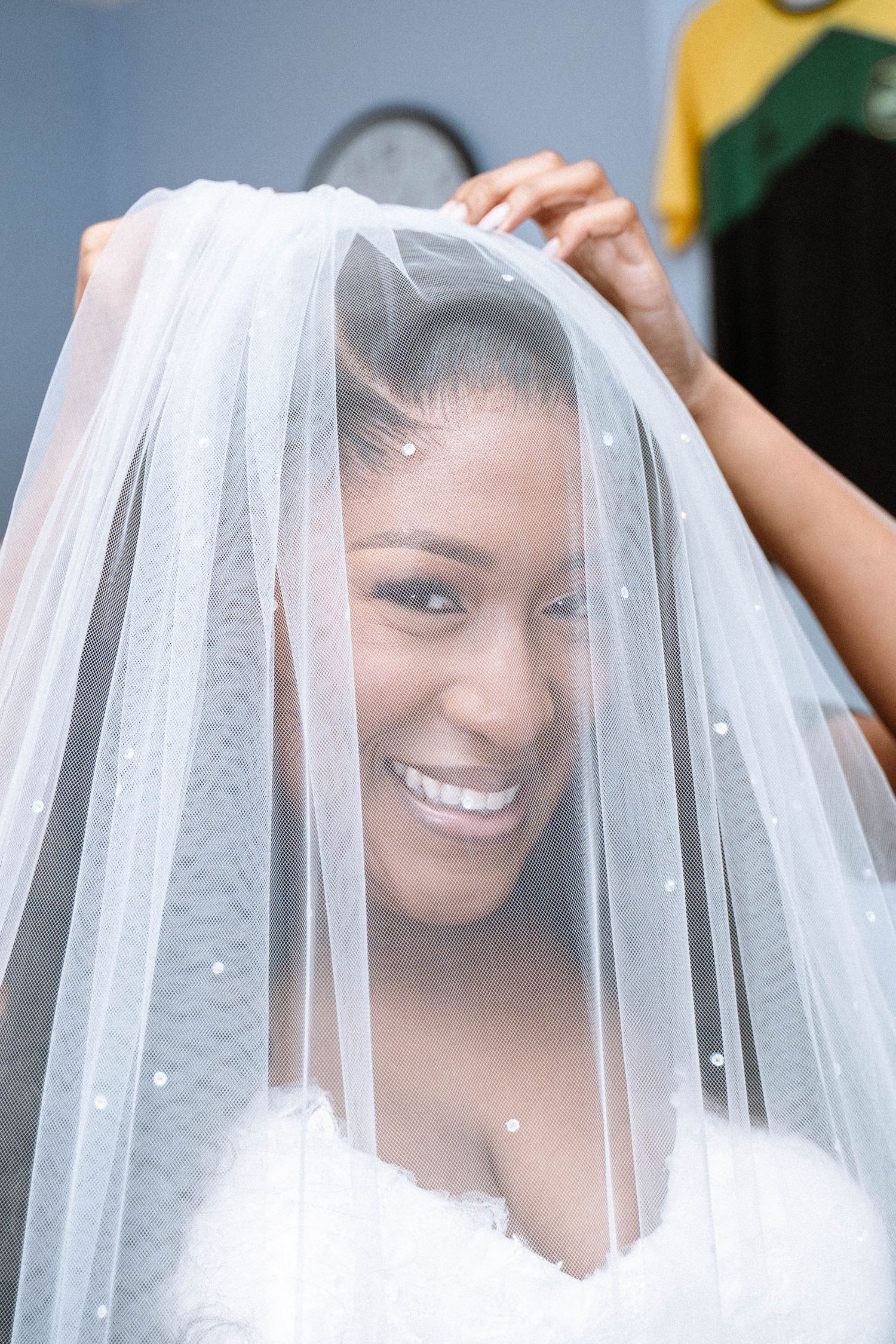 Bride smiling under veil during Jamaican church wedding in Birmingham