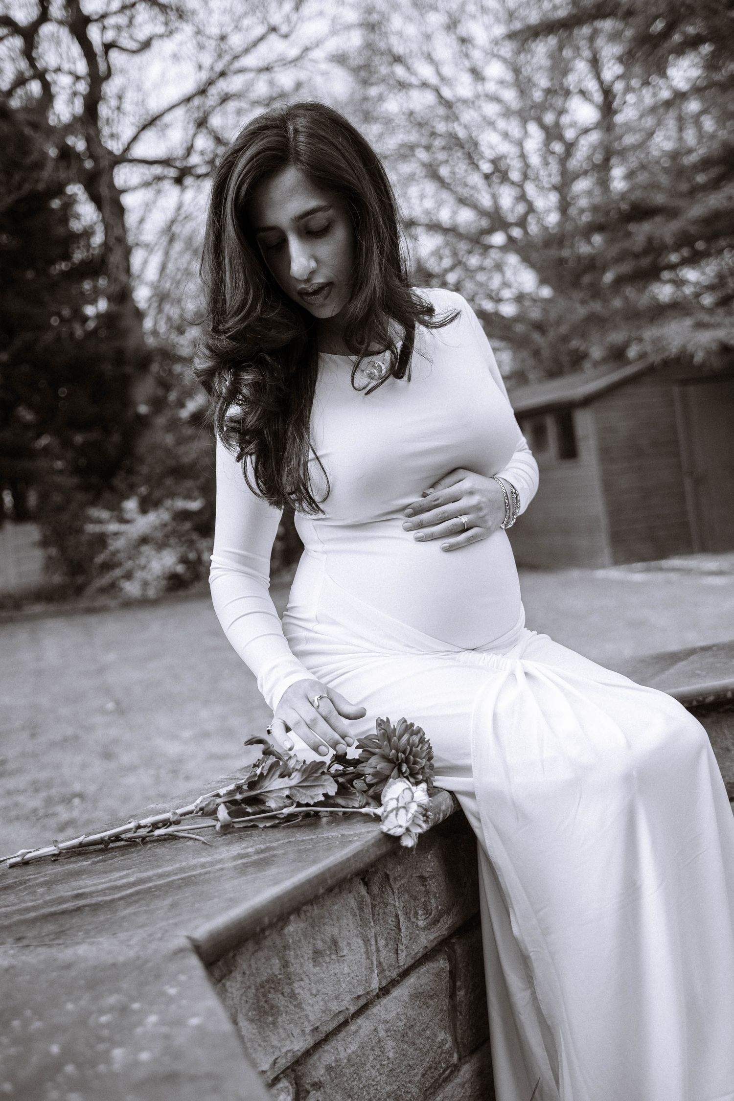 Pregnant woman sitting outdoors with flowers during a maternity photography session in Manchester