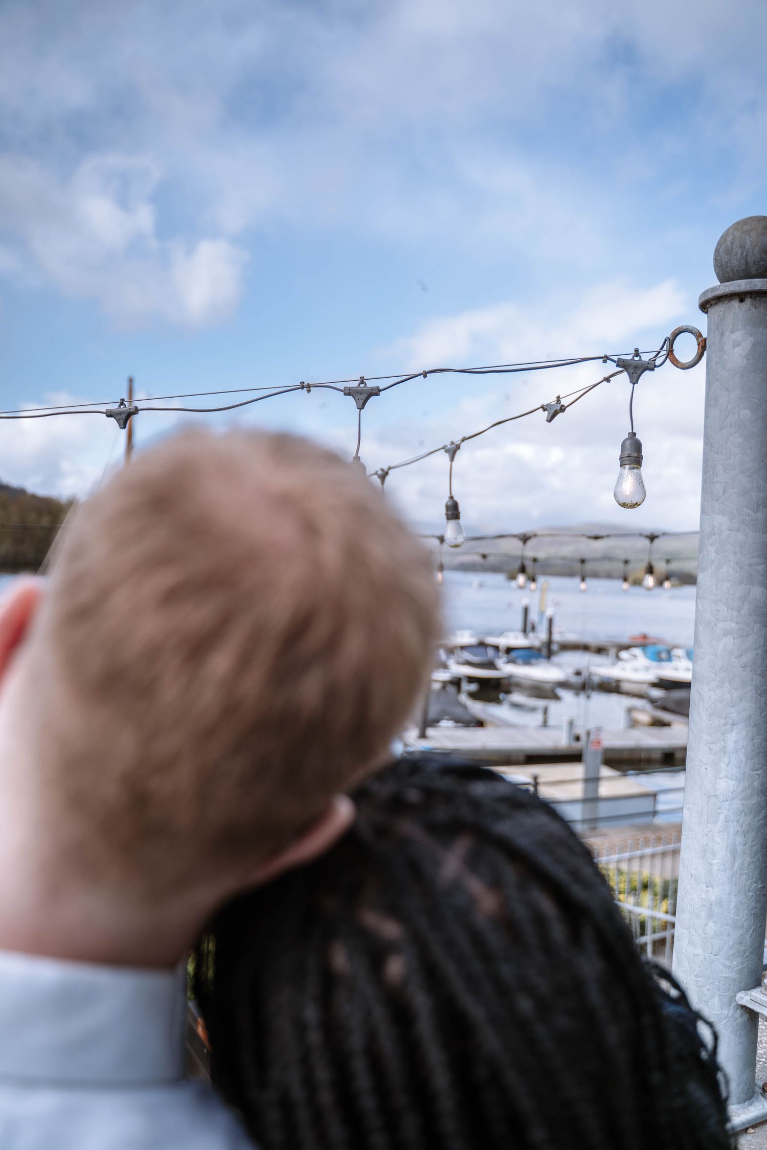Interracial couple standing together beside the water in Windermere, Lake District