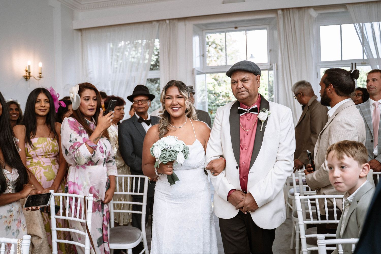 Bride walking down aisle with guests smiling during Enfield registry wedding ceremony