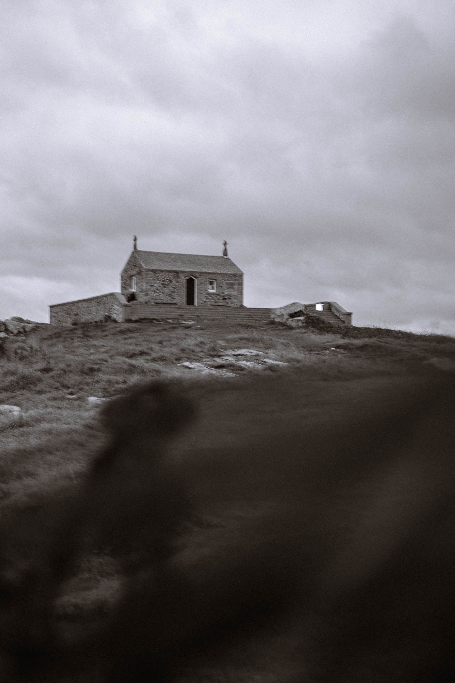 St Nicholas Chapel landscape view during a Cornwall elopement in St Ives with soft blurred foreground and grey skies