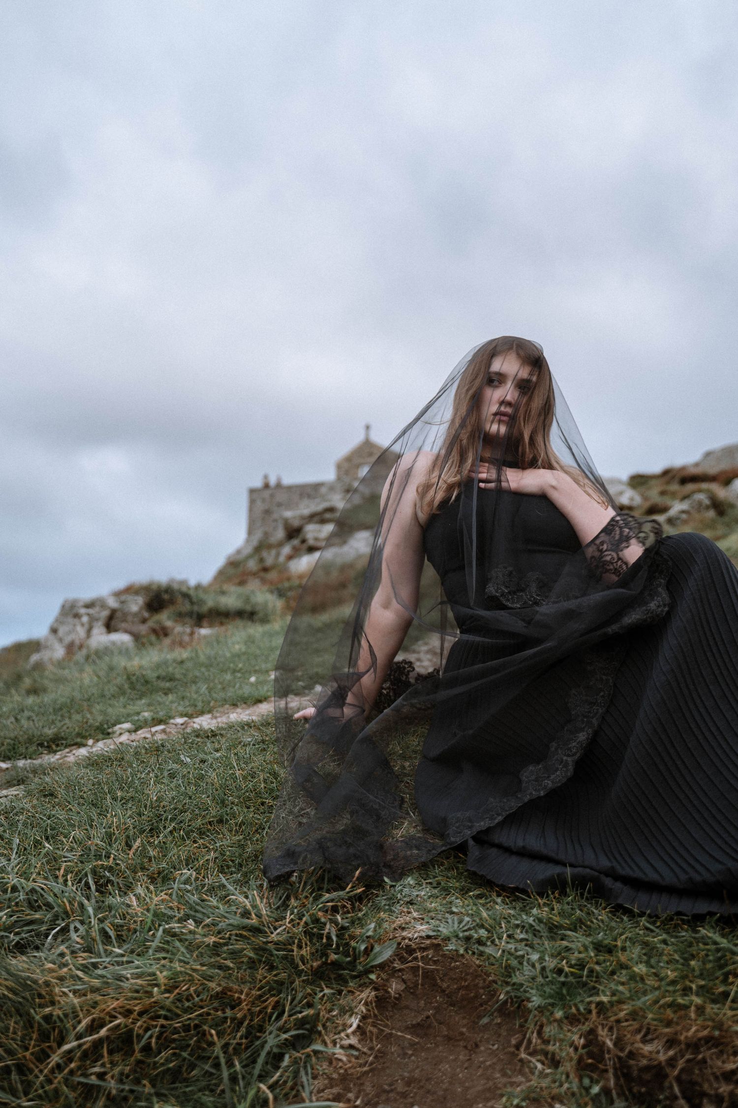 Cornwall gothic wedding elopement bride in black dress on cliffside moody sky cinematic editorial wedding photography UK