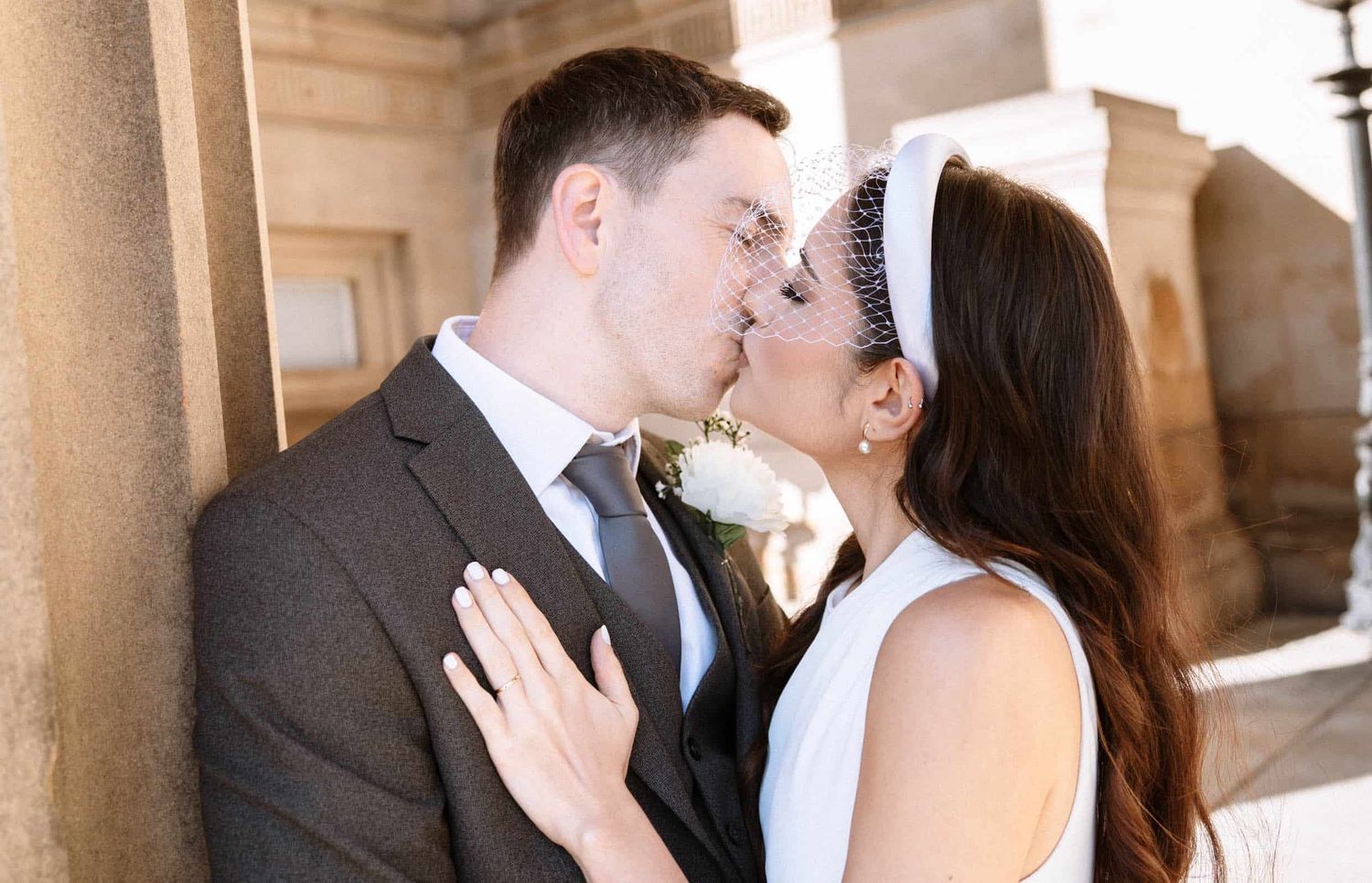 Couple kissing beneath the columns of St George Hall Liverpool during their wedding portraits.