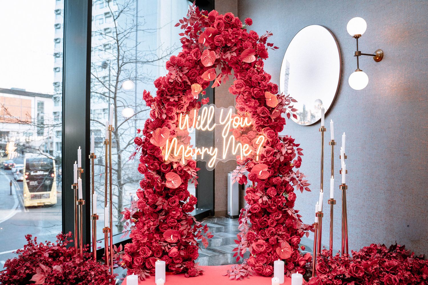 Romantic proposal setup with red floral arch and neon sign in Manchester