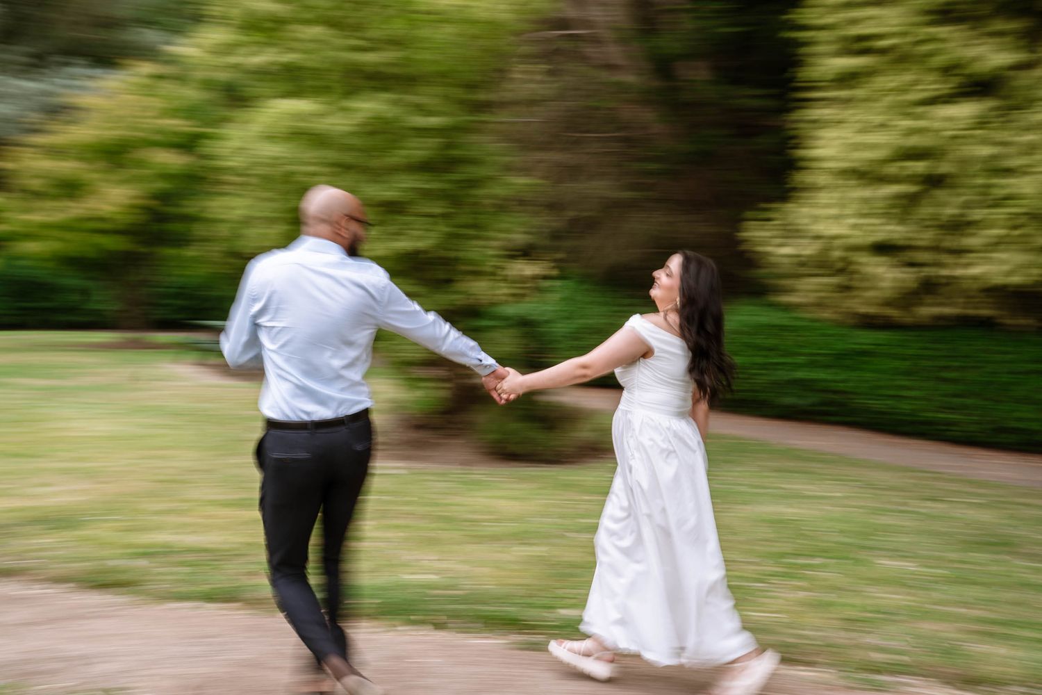Couple running hand in hand through the grounds at Fletcher Moss Park