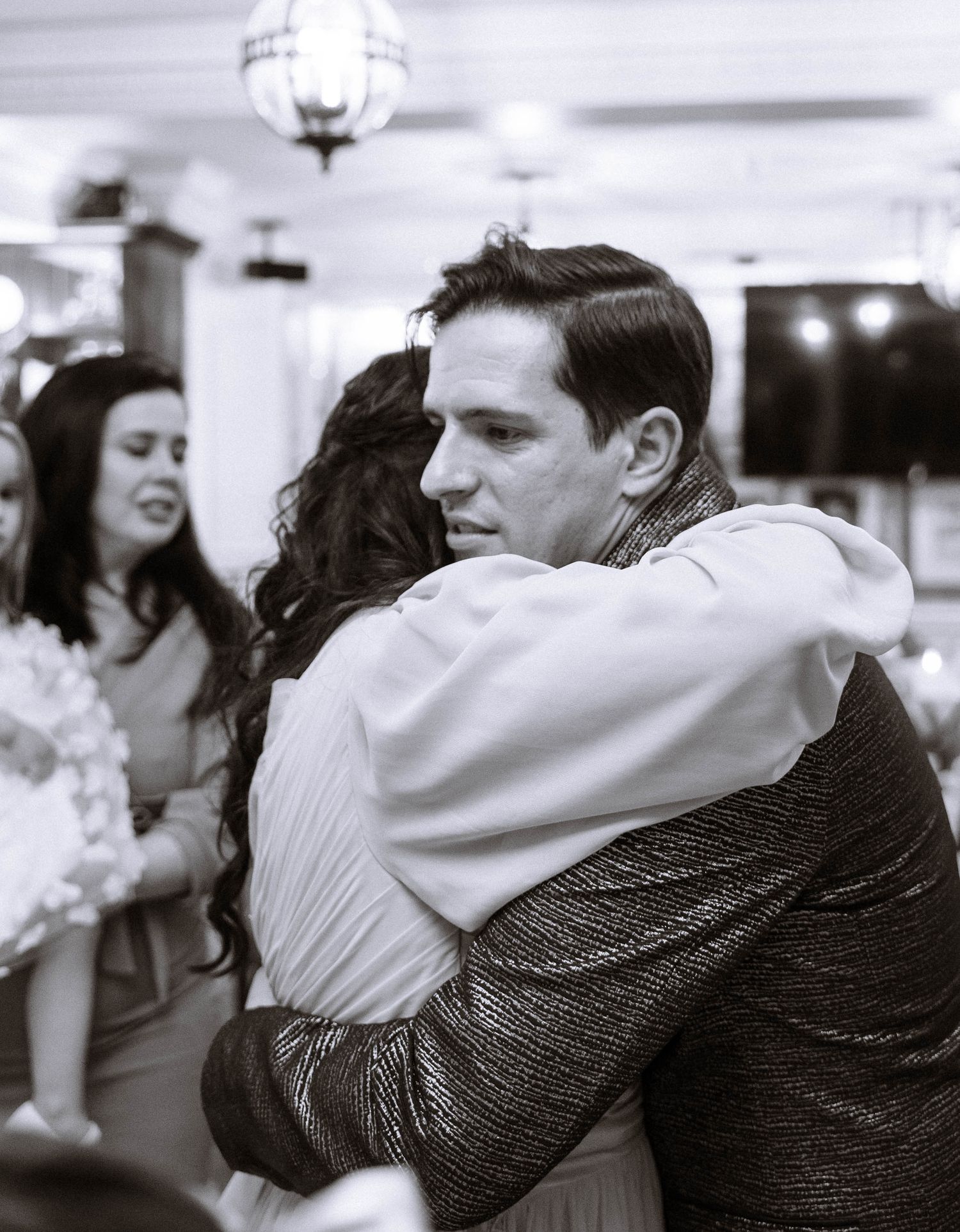 Emotional hug between guests during London wedding reception in black and white
