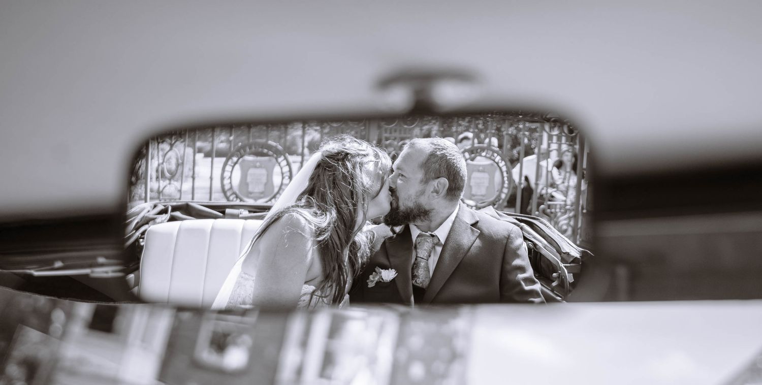 Couple kissing each other in a vintage car during a wedding at The Lodge in Wigan