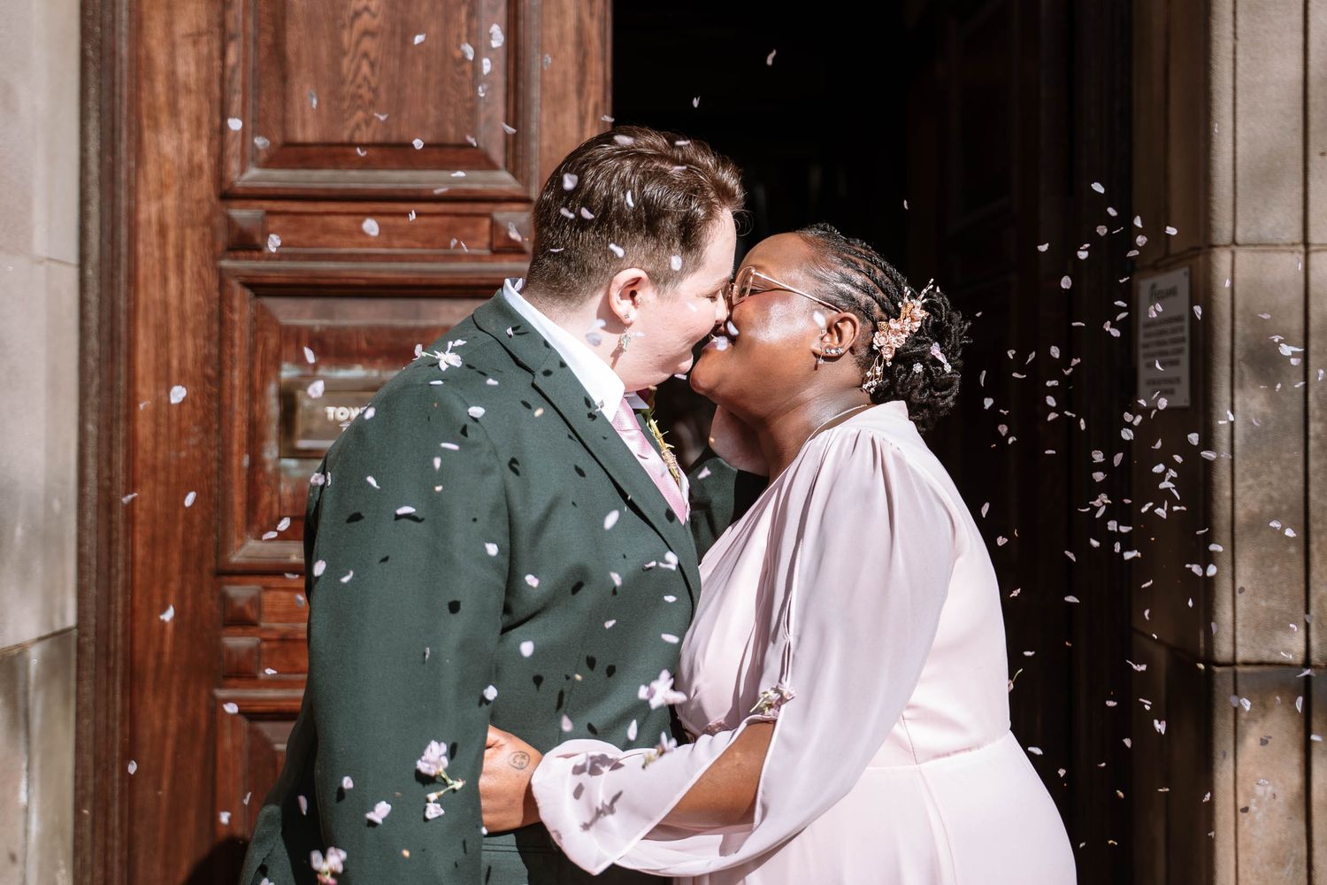 Couple kissing outside wooden doors during Manchester registry office wedding