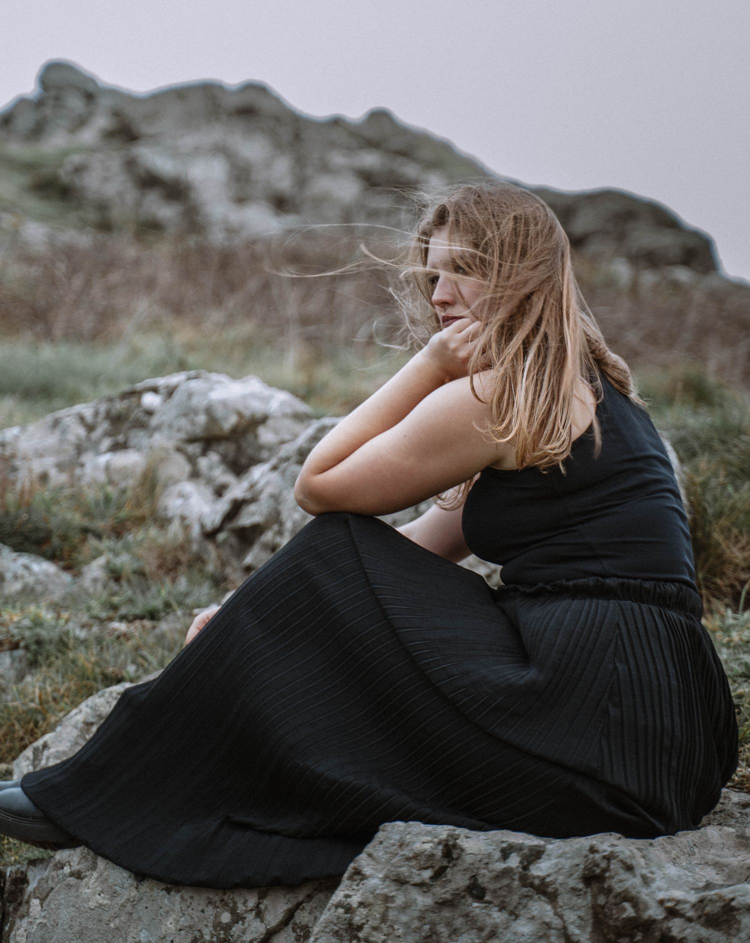 Seated portrait on rocky terrain in black dress during a St Ives Cornwall elopement with natural coastal backdrop
