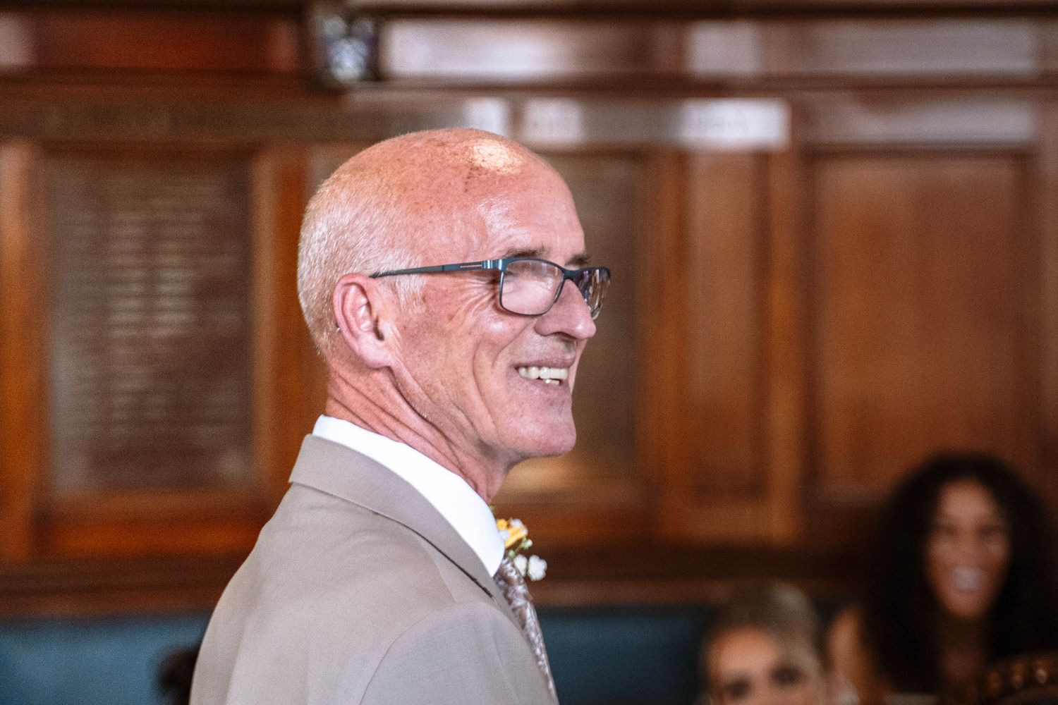 Man smiling during the ceremony inside Waterloo Town Hall, with the wood-panelled Council Chamber in view