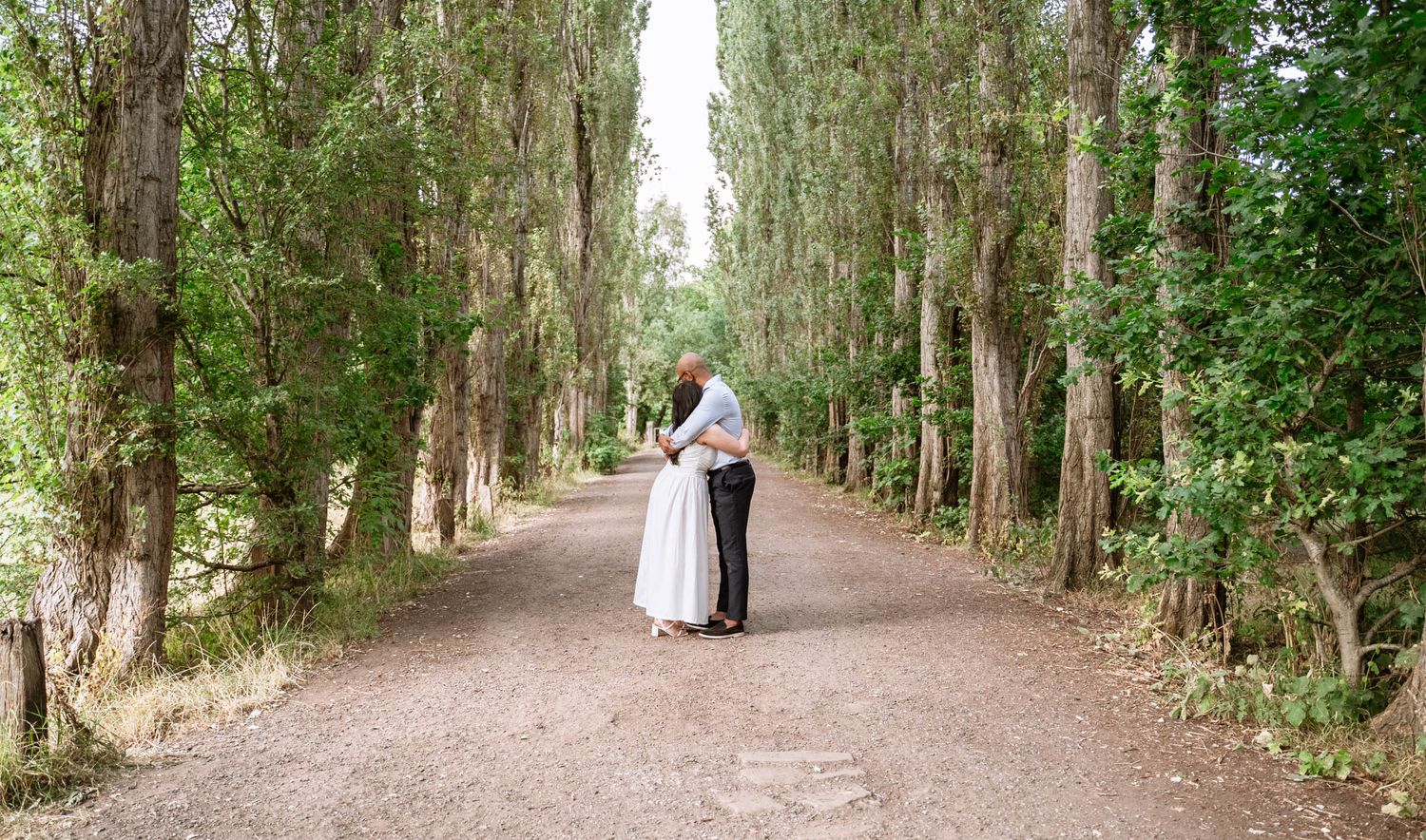 Couple standing together on a tree-lined path at Fletcher Moss Park