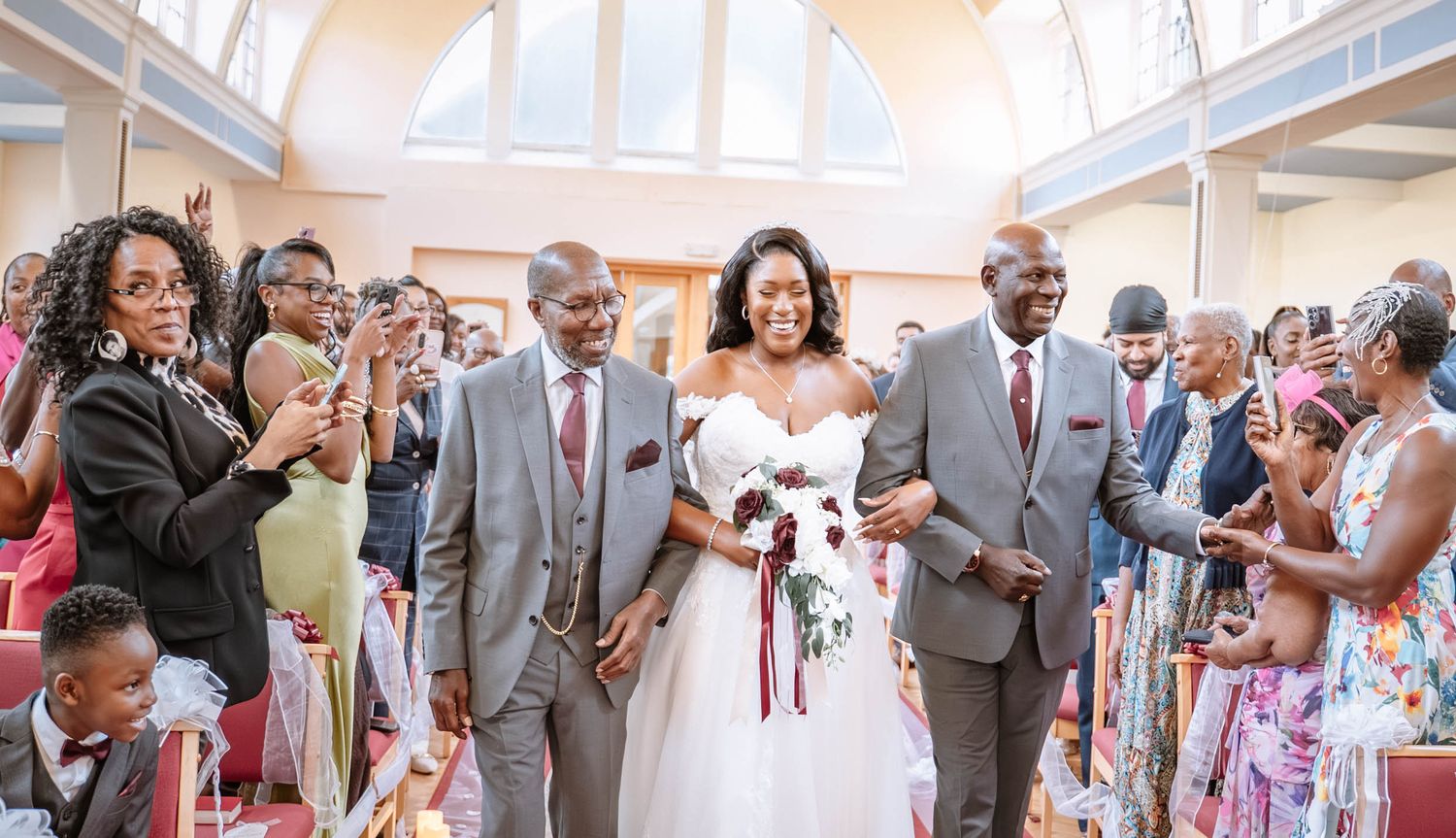 Bride walking down the aisle with her parents at a Jamaican church wedding in Birmingham