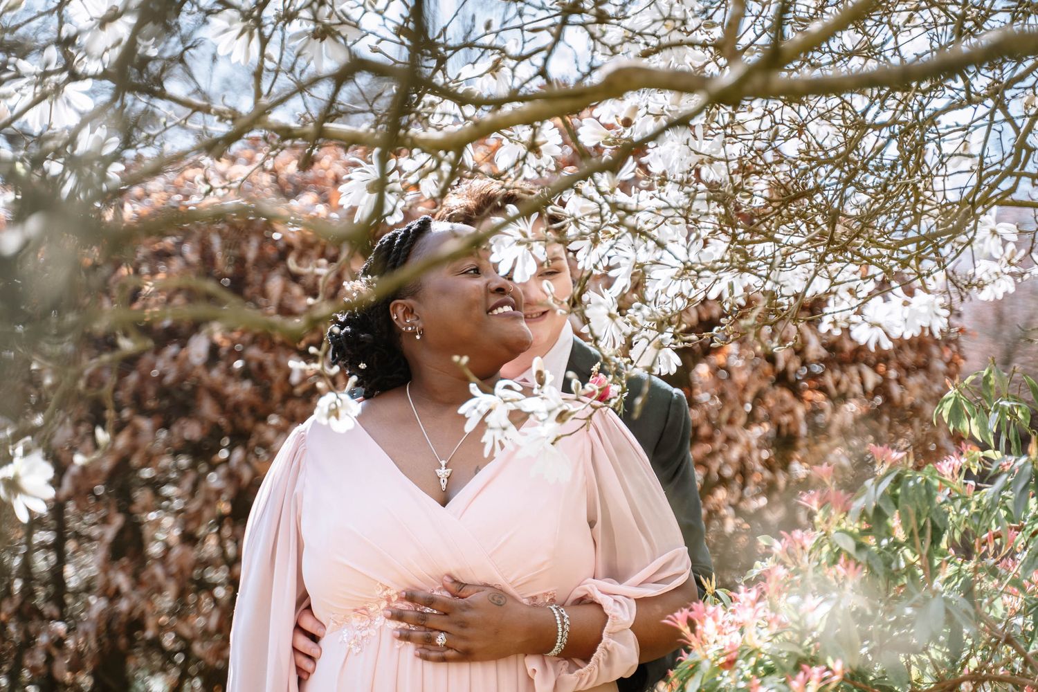 Bride smiling under trees during Manchester LGBTQ wedding portraits