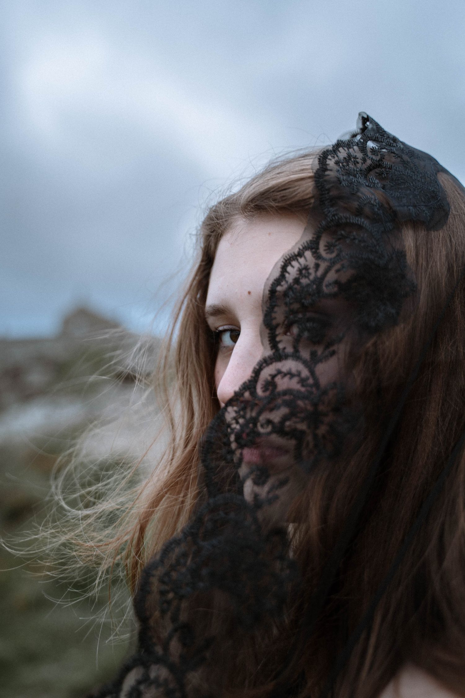 Close-up portrait with black lace veil covering face during a Gothic St Ives Cornwall elopement on the coast