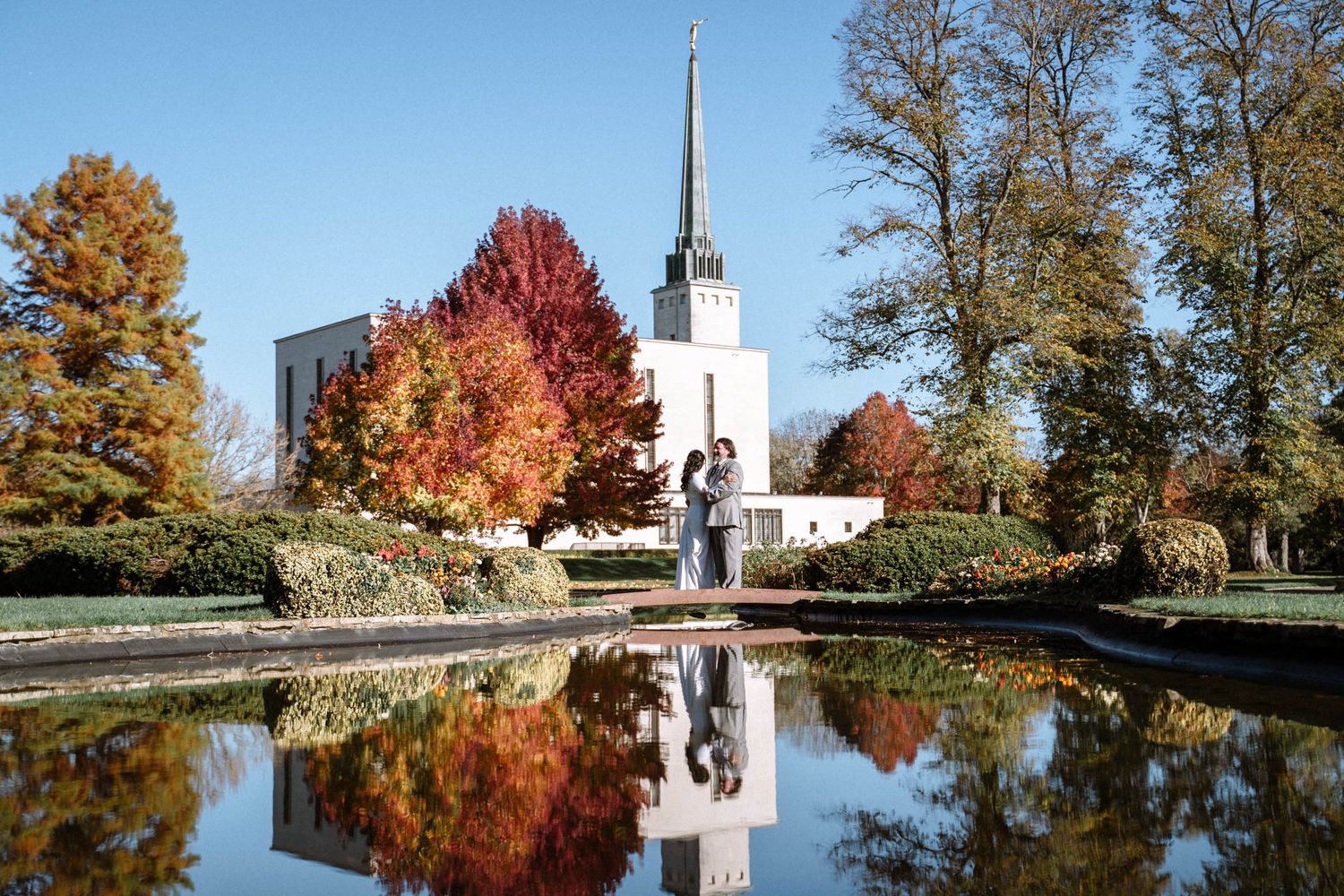LDS temple reflected in water with autumn trees during wedding photography in London