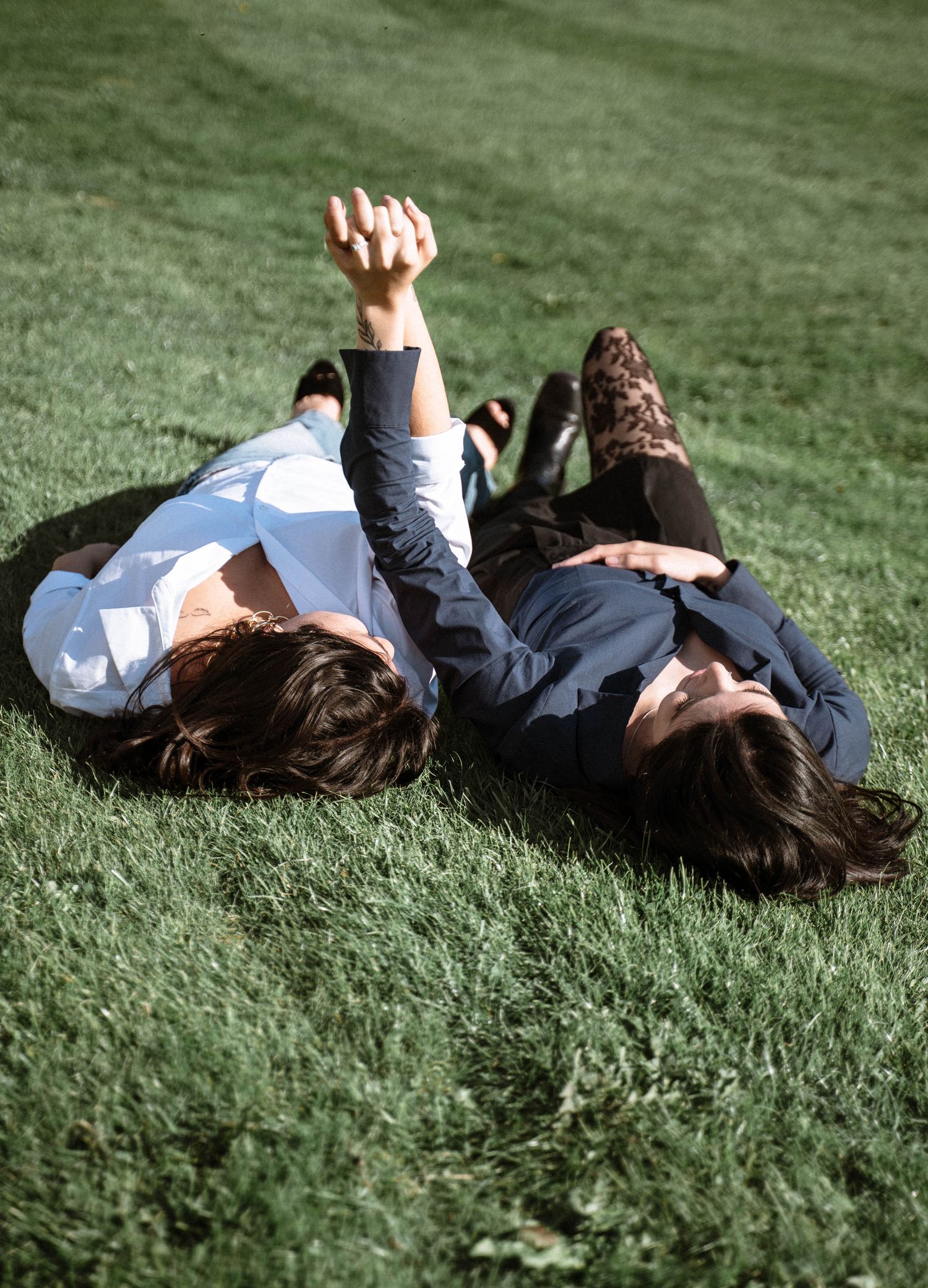 Cardiff proposal photoshoot couple lying on grass laughing together during engagement session in Wales park setting