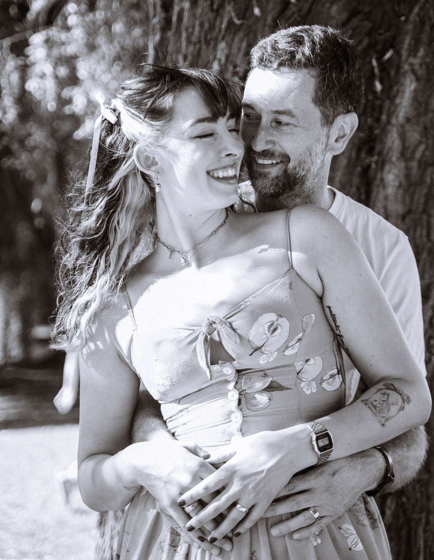 Black and white photo of a couple laughing at each other in a park in Cambridge after their proposal