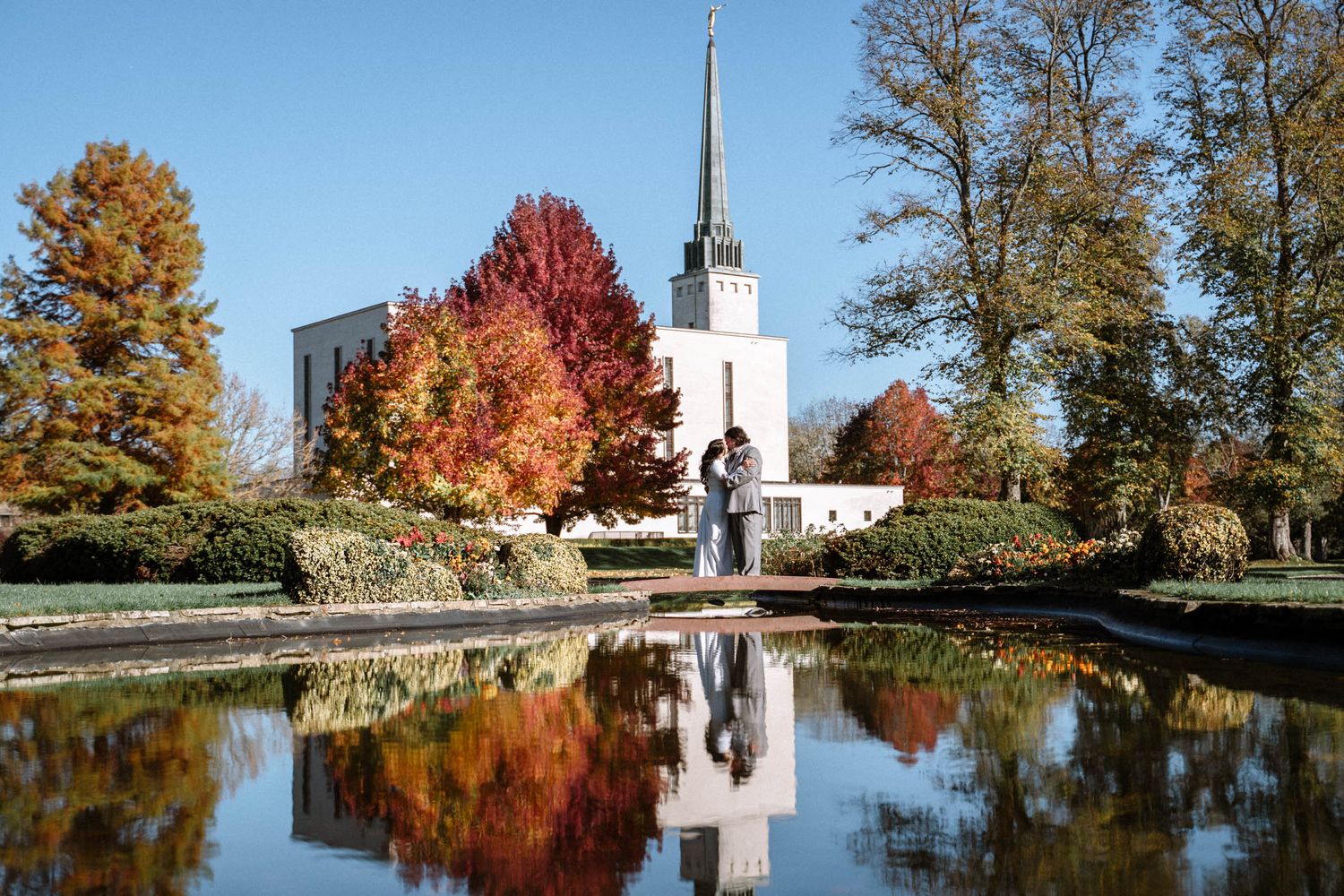 Mormon Couple standing in front of London LDS Temple before their wedding ceremony kissing