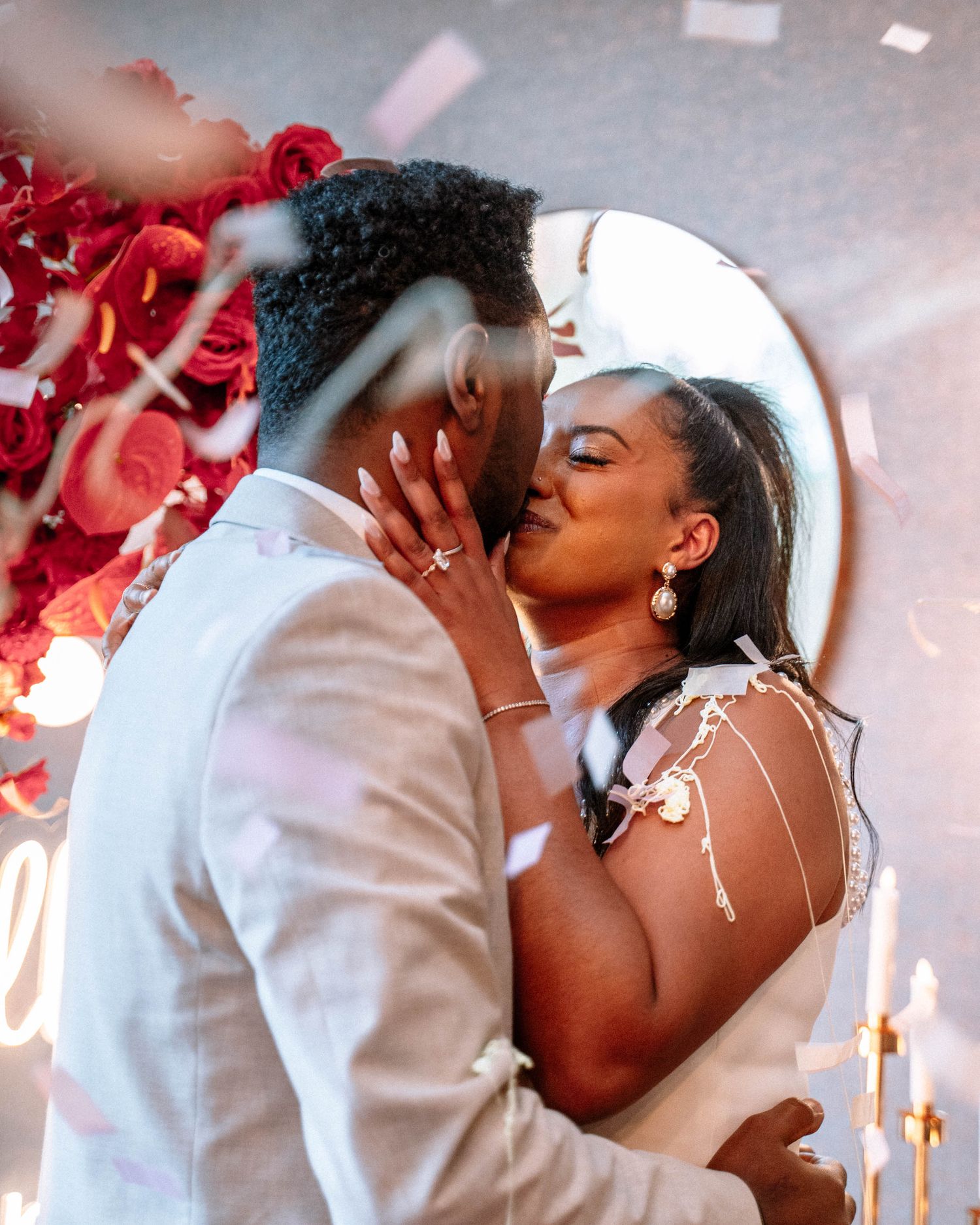 Couple kissing after a proposal surrounded by red floral decorations in Manchester