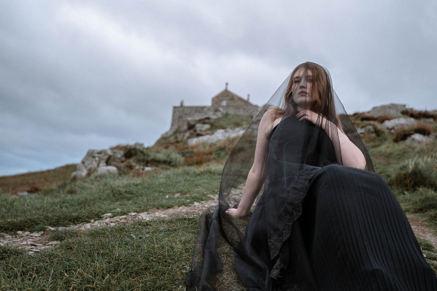 Person in black dress with veil near St Nicholas Chapel during a St Ives Cornwall elopement under overcast skies