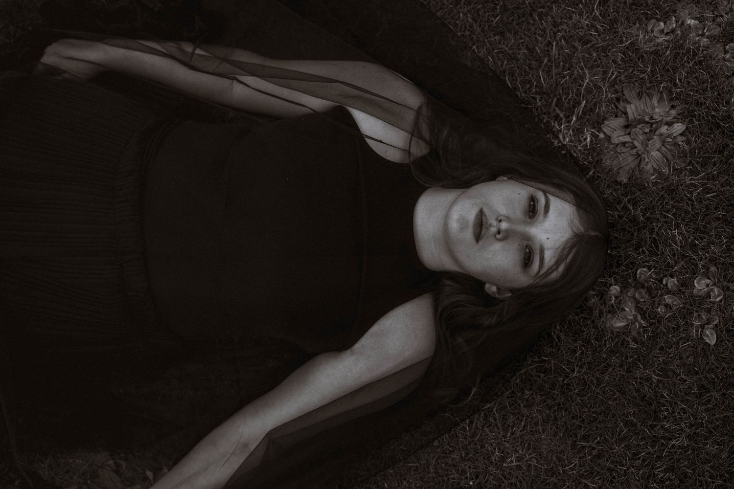 Moody overhead portrait lying on grass in black dress during a Cornwall elopement with gothic aesthetic in St Ives