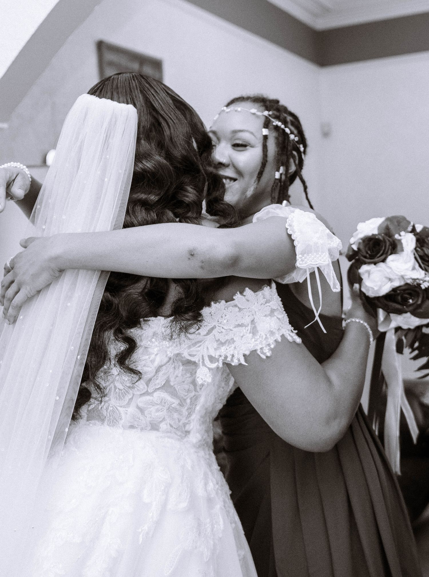 A bridesmaid hugging a bride during a Jamaican wedding in birmingham in black and white