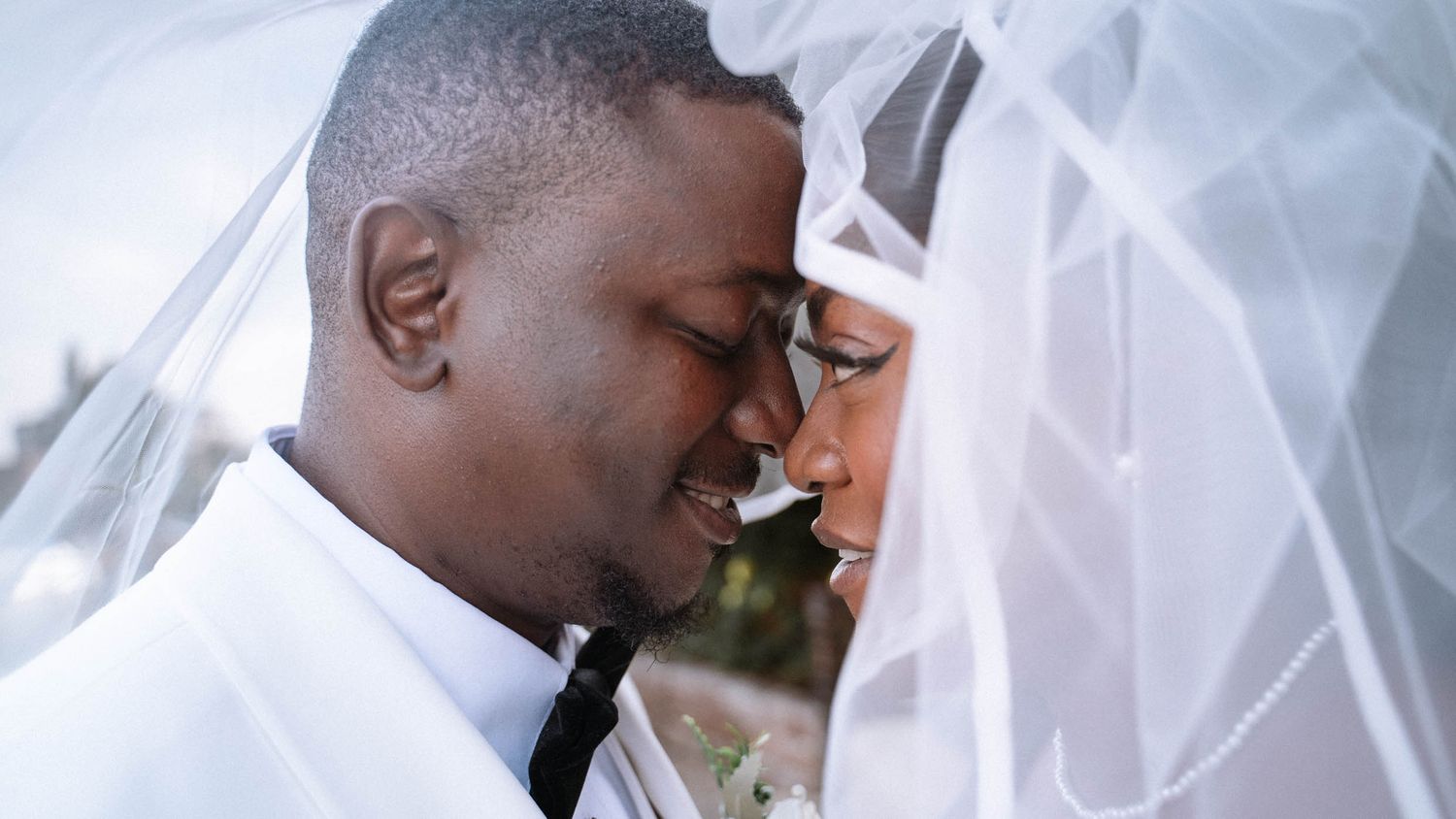 Groom and bride touching foreheads beneath a wedding veil at Ravens Ait