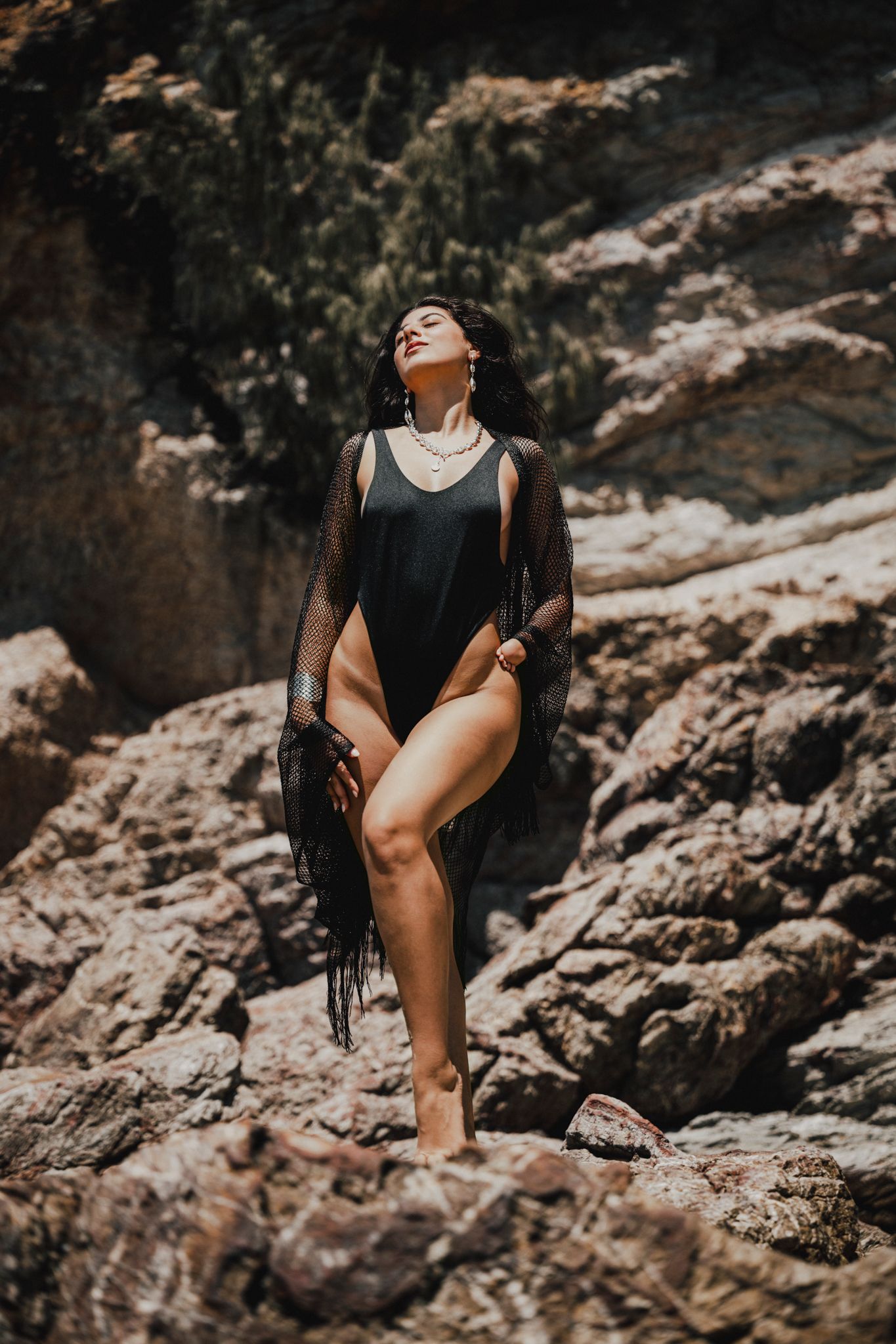 Artistic fashion photography on rocky terrain with dramatic shadows and poses.
