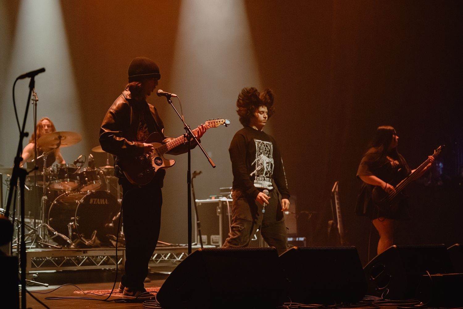 Band performing on stage with warm amber lighting creating silhouettes of musicians.