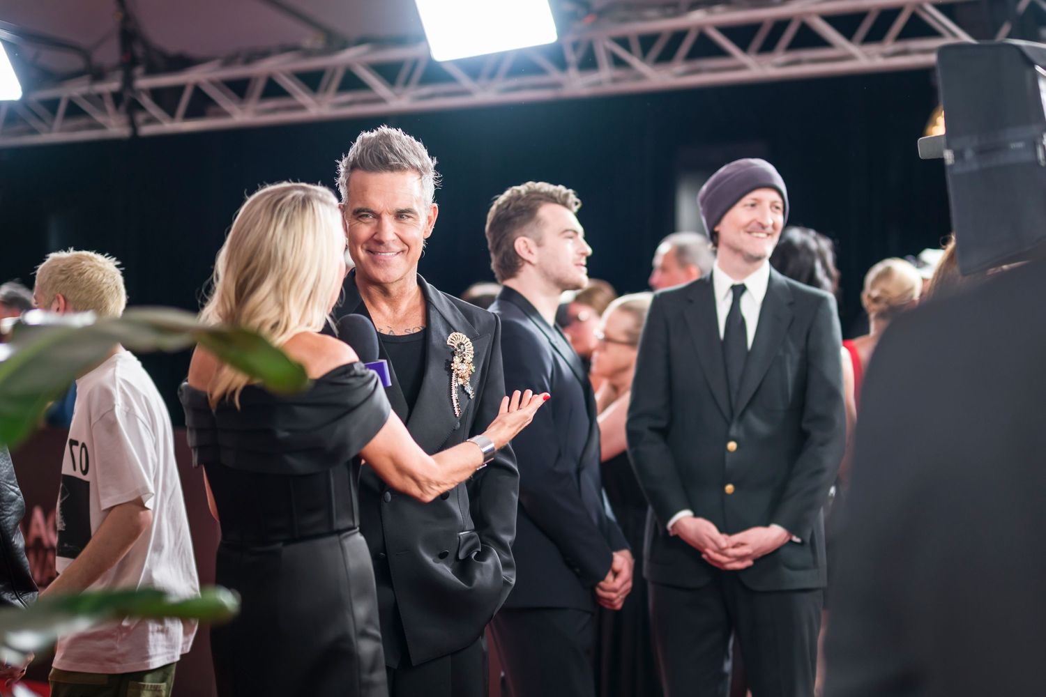 Guests mingling and chatting during formal event on red carpet.
