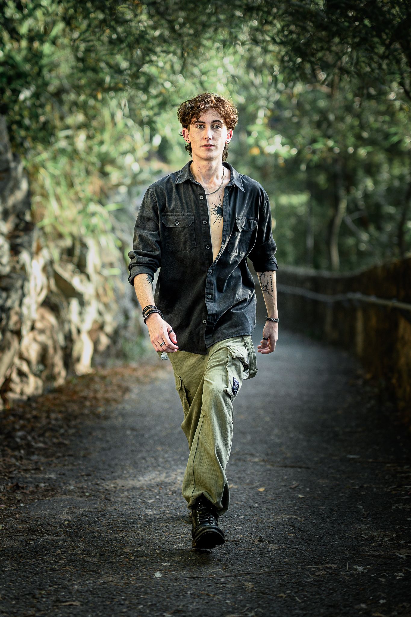 Person in black shirt and khaki pants runs along a shaded forest path.