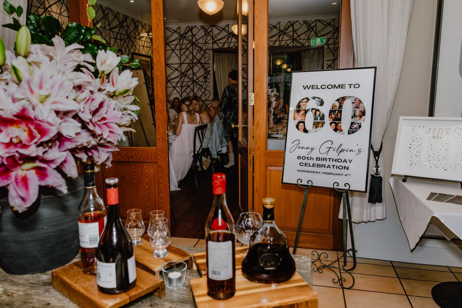 Wine bottles and floral arrangements displayed on wooden table with decorative signage.