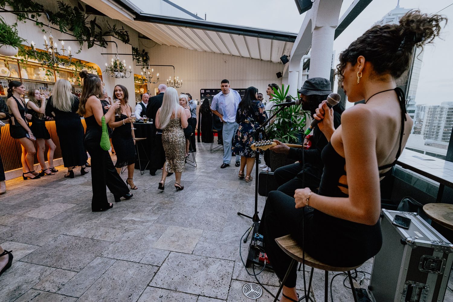 Outdoor rooftop event with musicians performing for gathered crowd.
