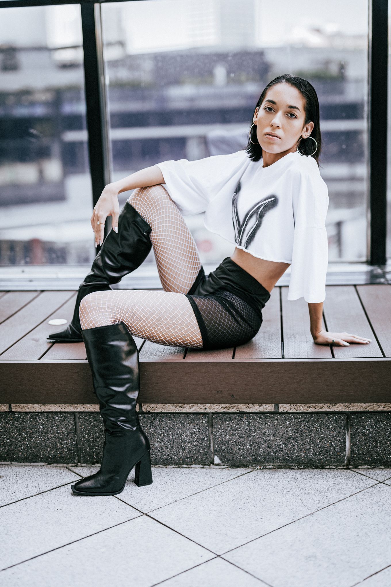 Fashion editorial featuring black and white outfit with boots on urban concrete setting.