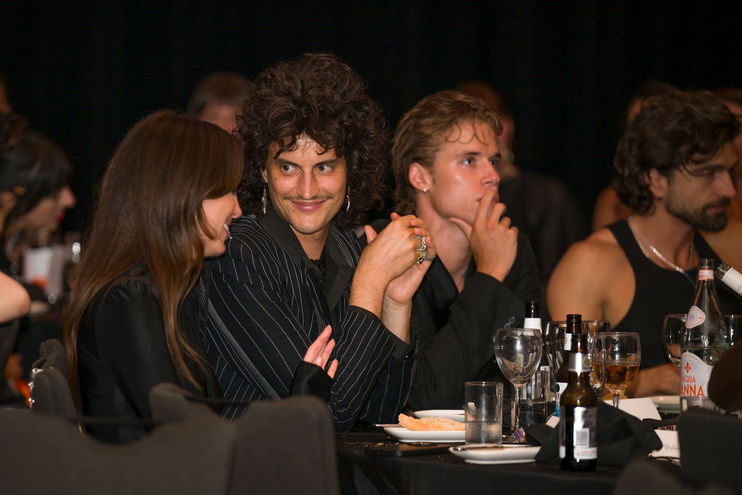 Guests engaged in conversation while seated at a dark table during an evening event.