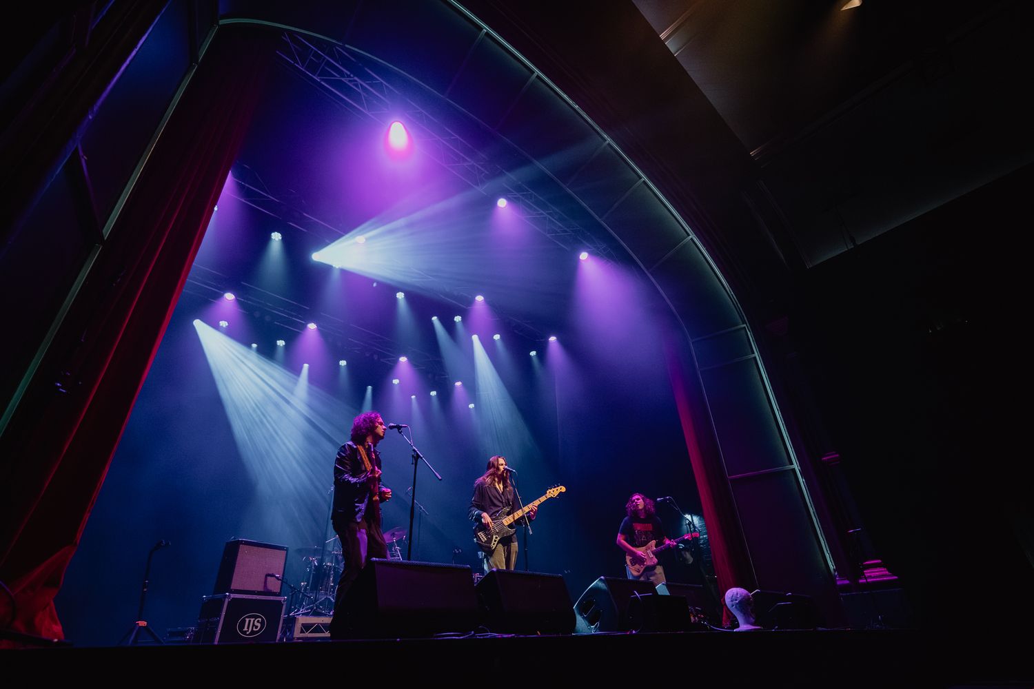 Wide angle concert stage view with purple lighting and musicians performing.
