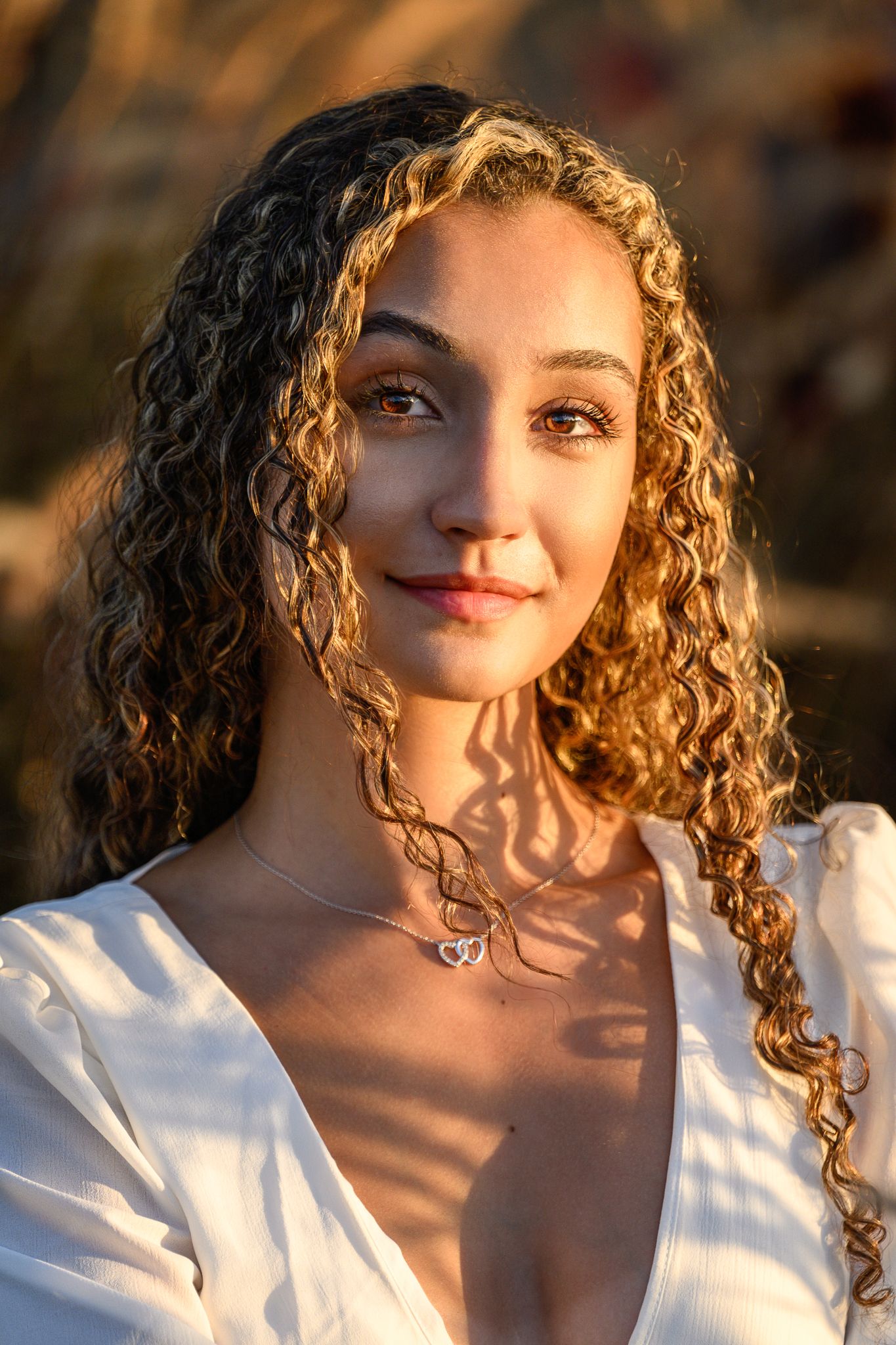 Close-up portrait with natural lighting and curly hair against warm sunset glow.