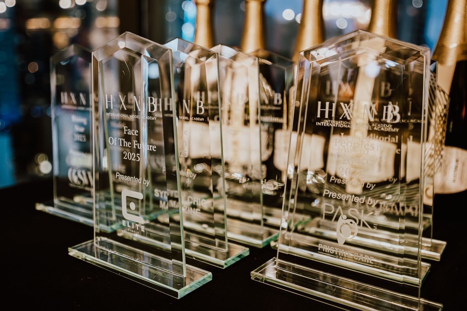 Close-up of crystal award trophies displayed on dark surface with golden lighting.
