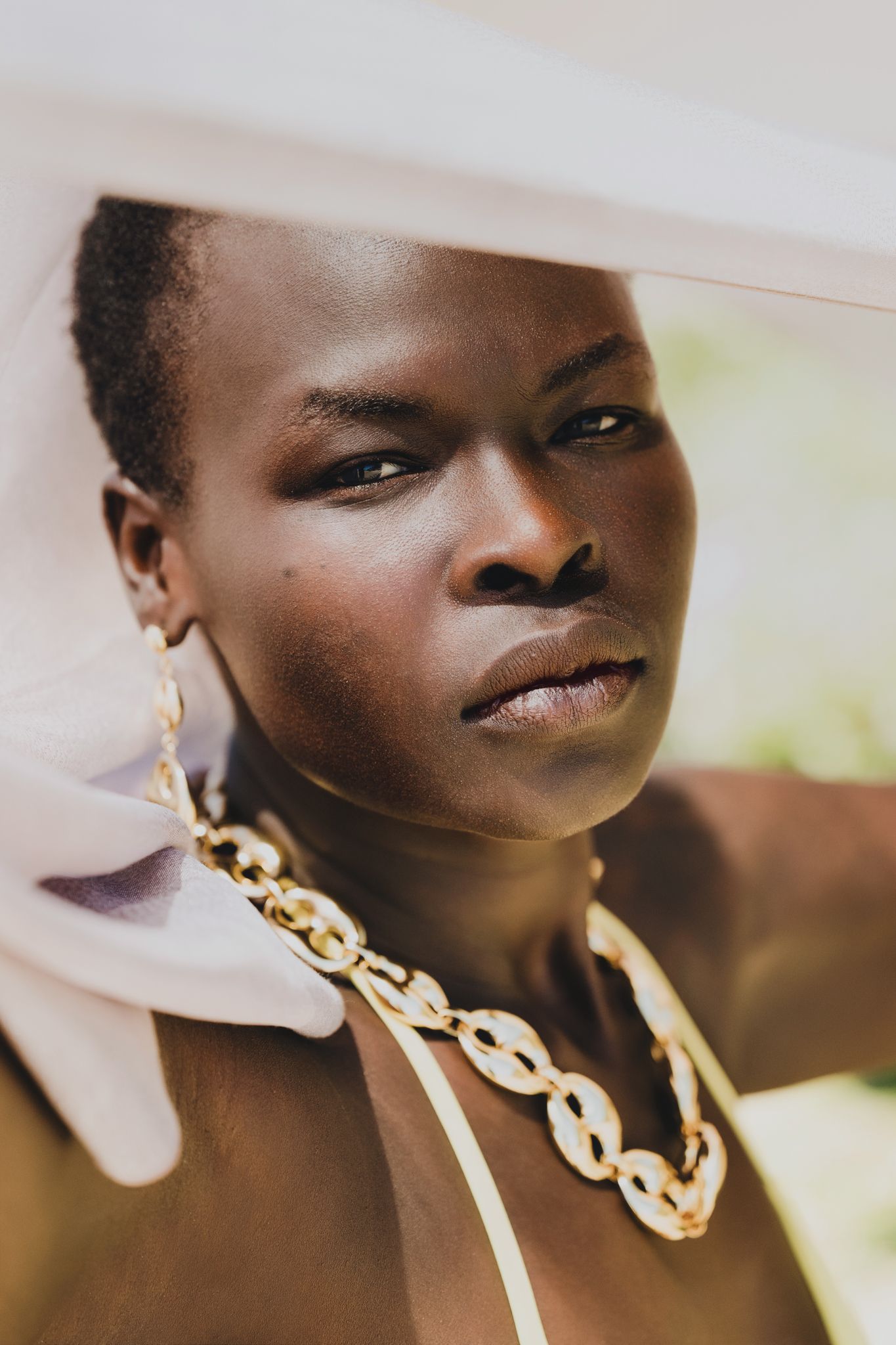 Fashion portrait of a model wearing a bold chain necklace against a soft background.
